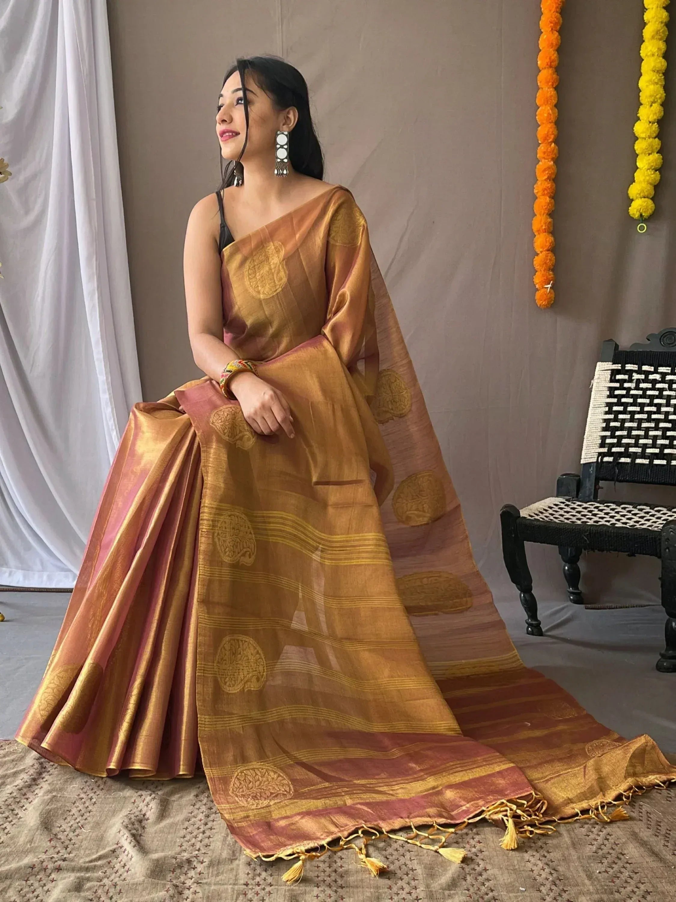 Woman in golden-brown ethnic saree with circular motifs and tassels, styled for festive occasions
