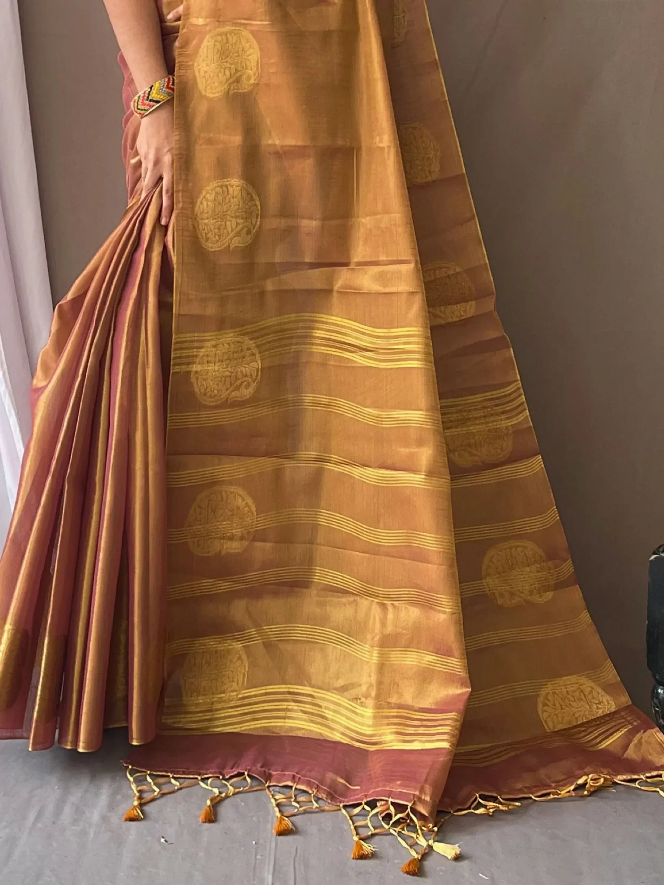 Golden ethnic saree with circular motifs and tassels, perfect for Indian occasions