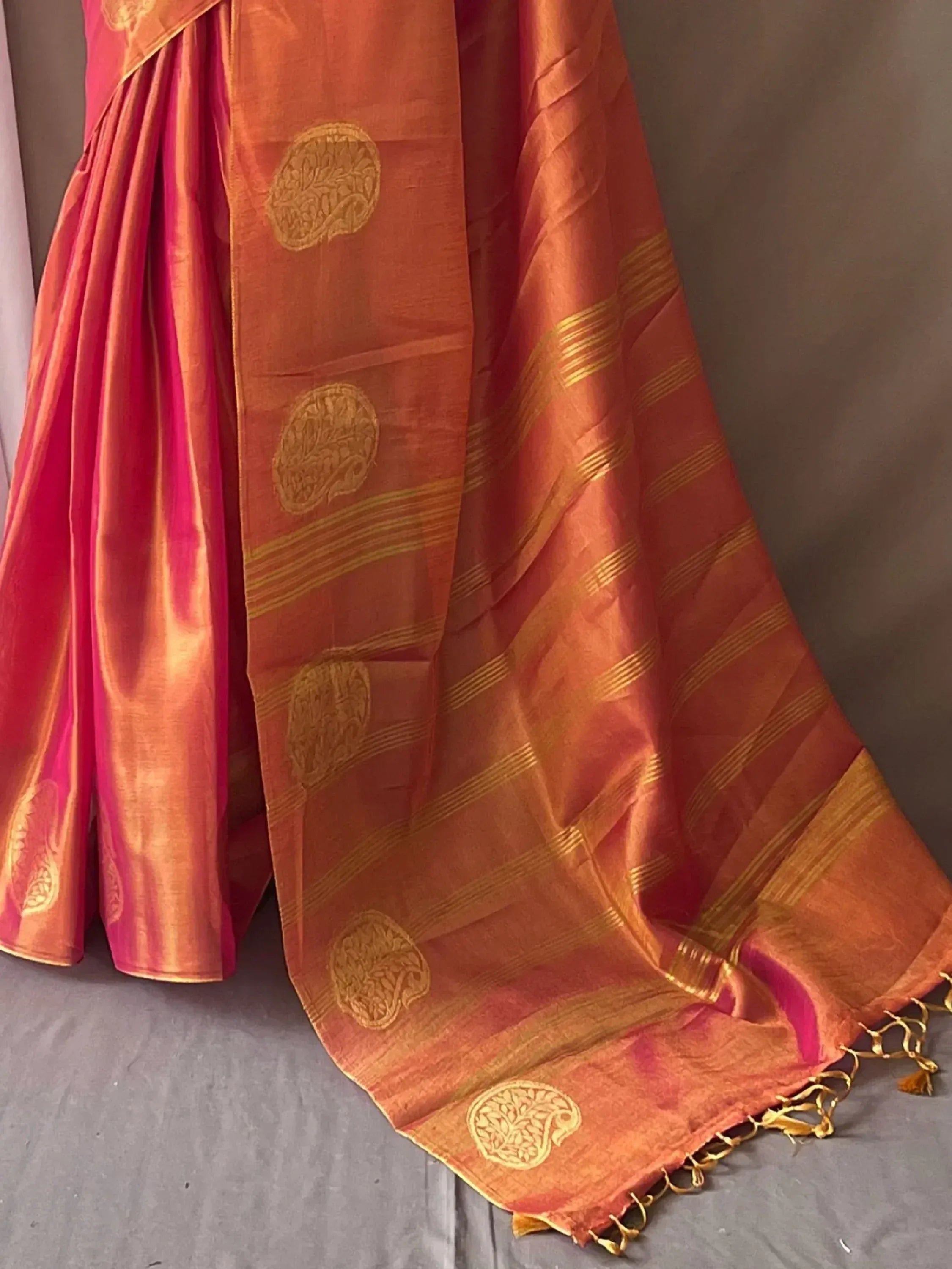 Orange and pink silk saree with gold paisley motifs and striped border, ideal for Indian ethnic wear