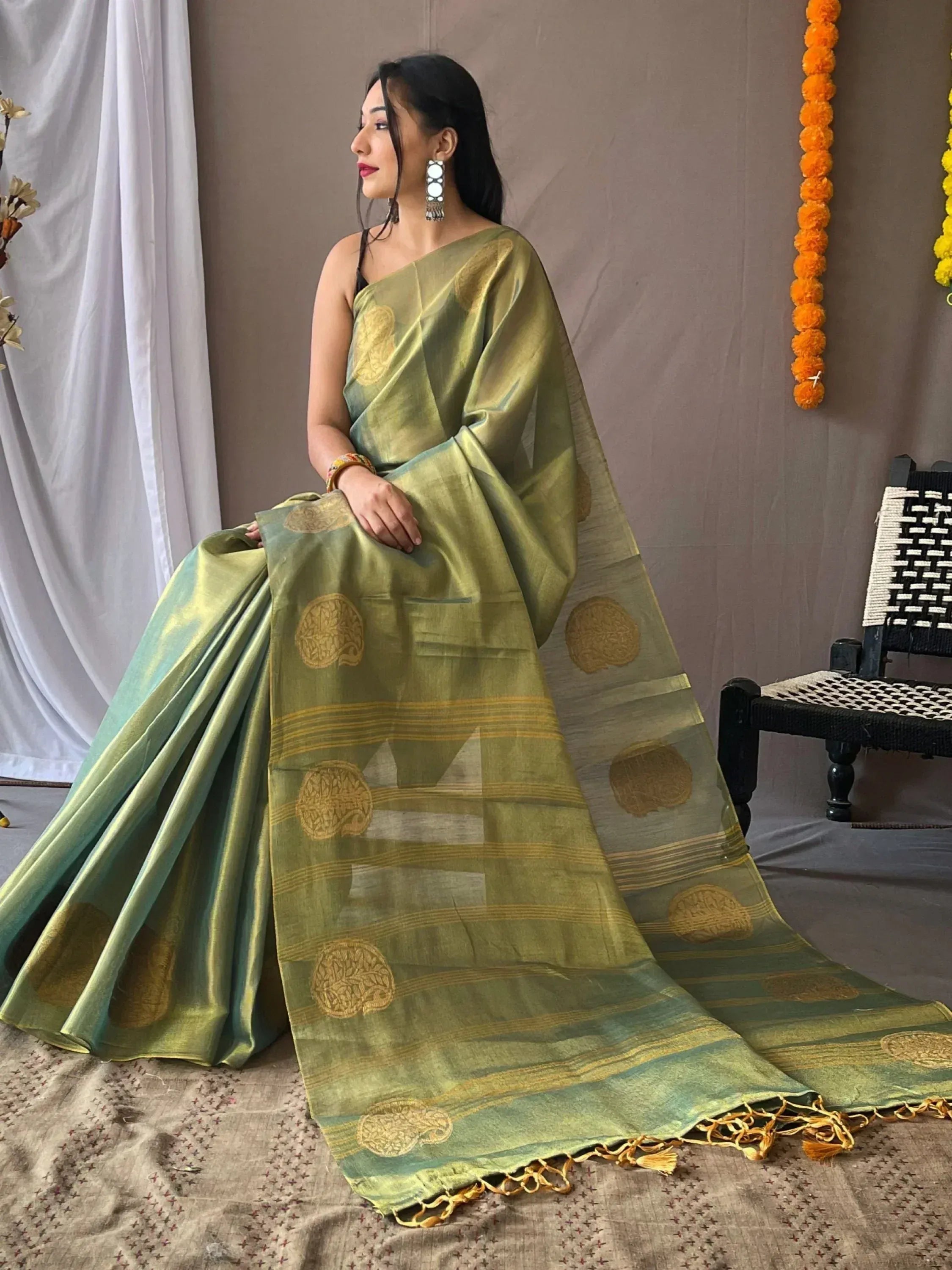 Olive green saree with gold circular motifs and tassels, styled for ethnic wear