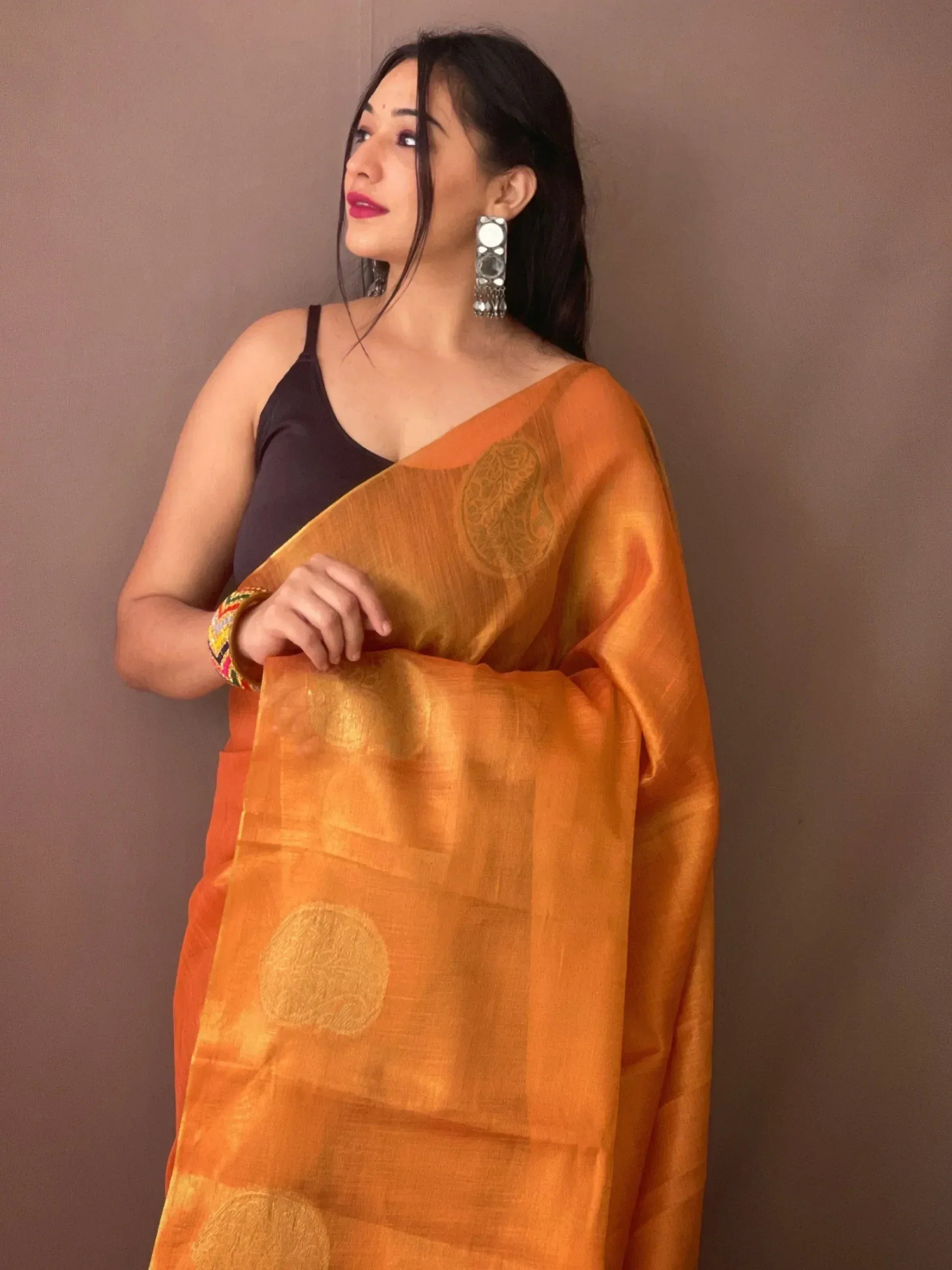 Woman in orange designer saree with gold paisley motifs, ethnic wear for festive occasions