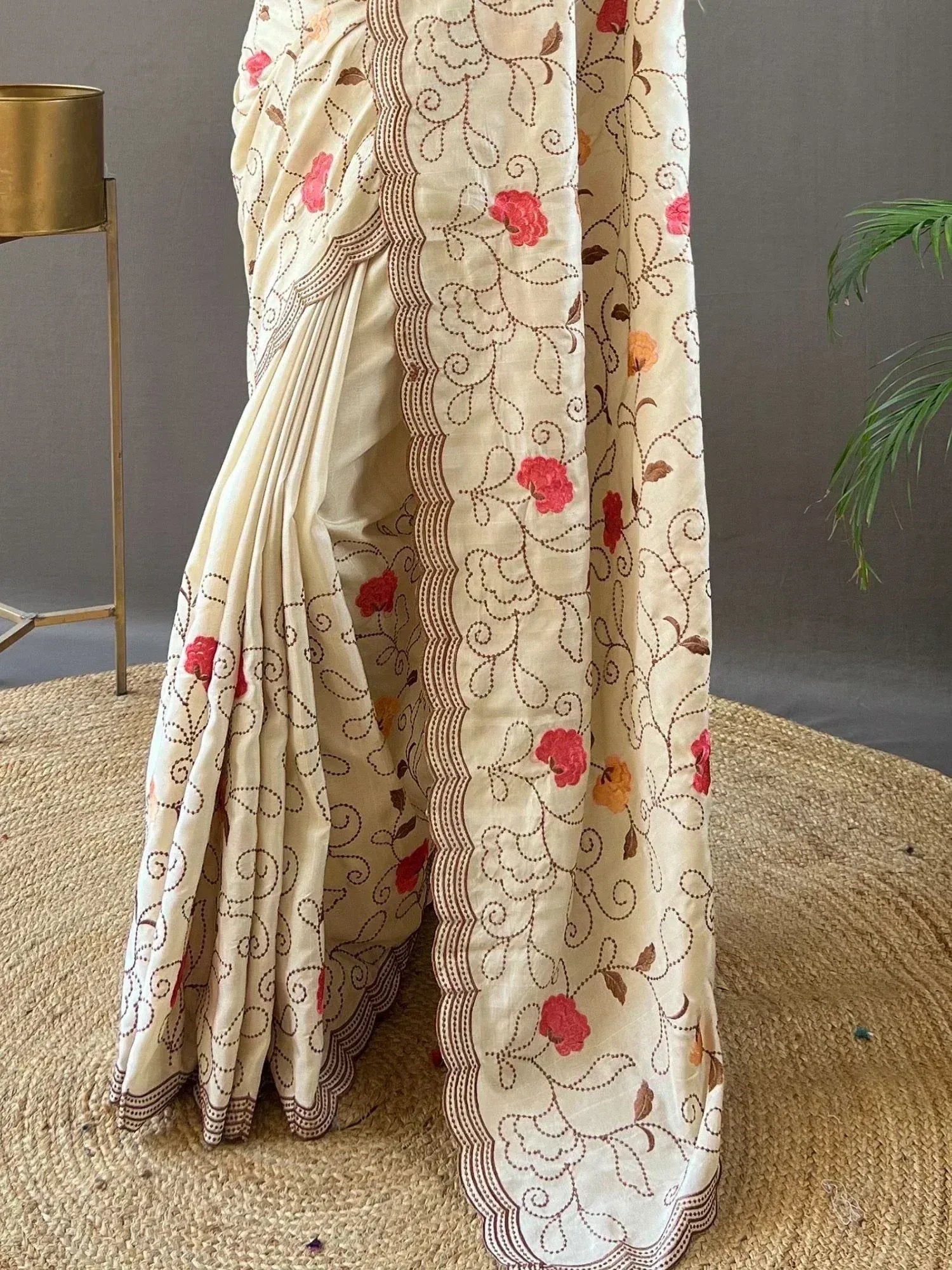 Cream saree with floral embroidery and scalloped border, ideal for ethnic wear occasions