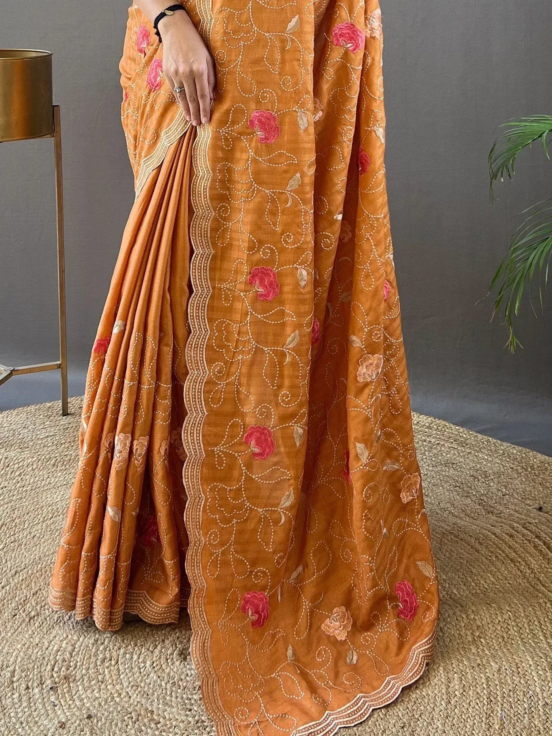 Orange embroidered saree with pink floral motifs and scalloped border, ideal for Indian ethnic wear