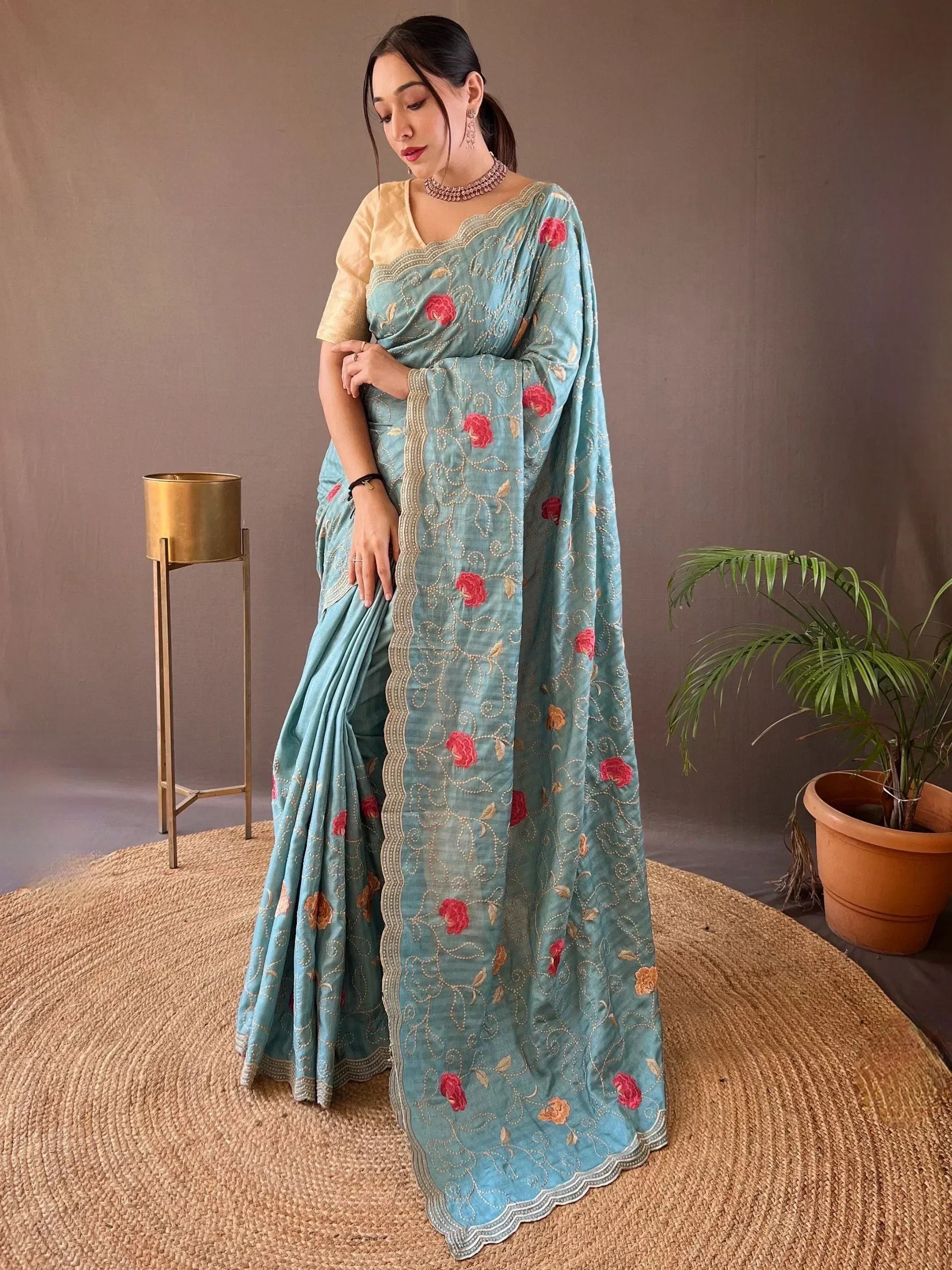 Teal embroidered saree with pink floral motifs and gold detailing, paired with a golden blouse, ideal for Indian ethnic wear.