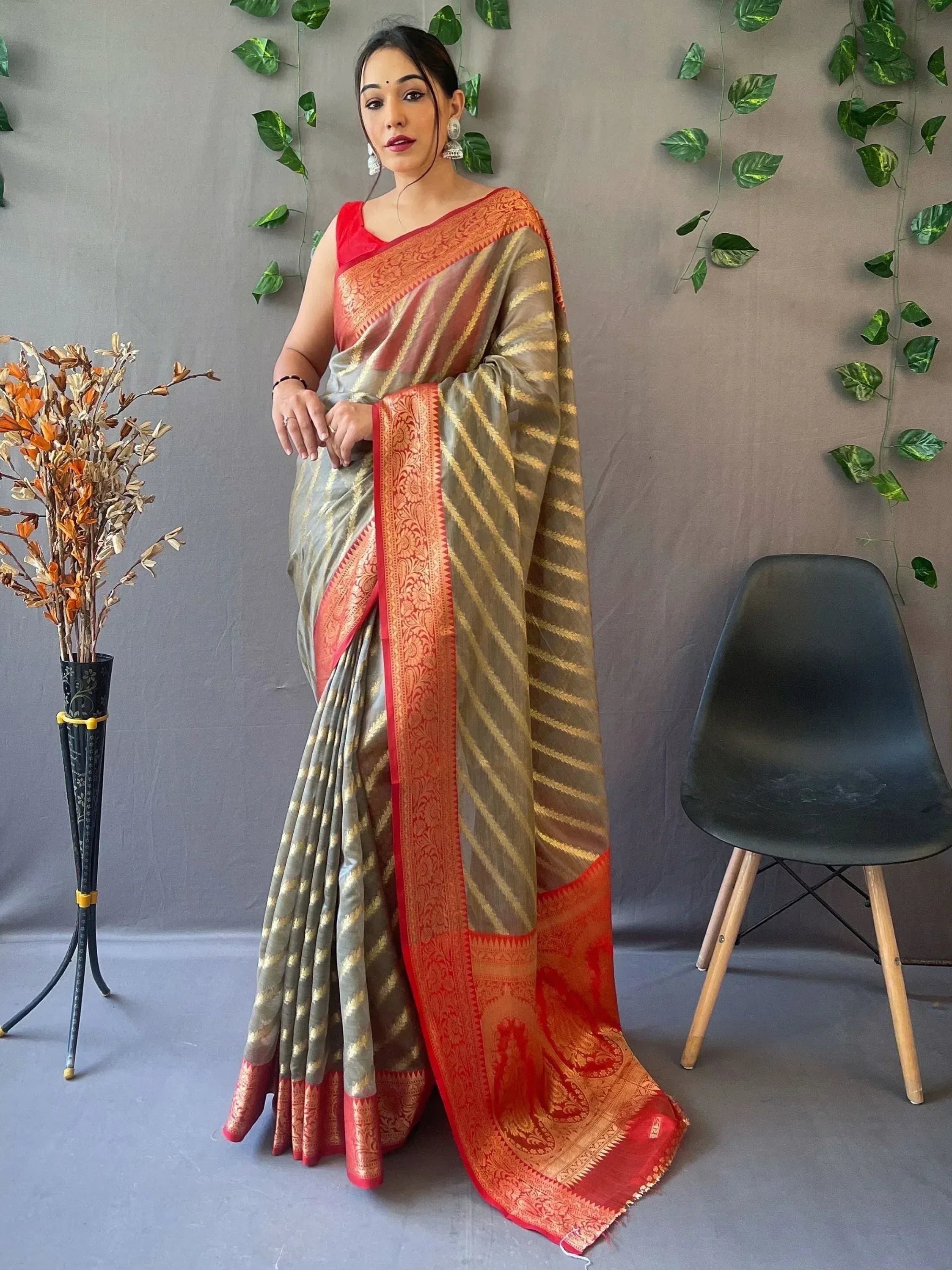 Woman in elegant grey and orange saree with gold stripes and intricate border, perfect for Indian ethnic occasions.