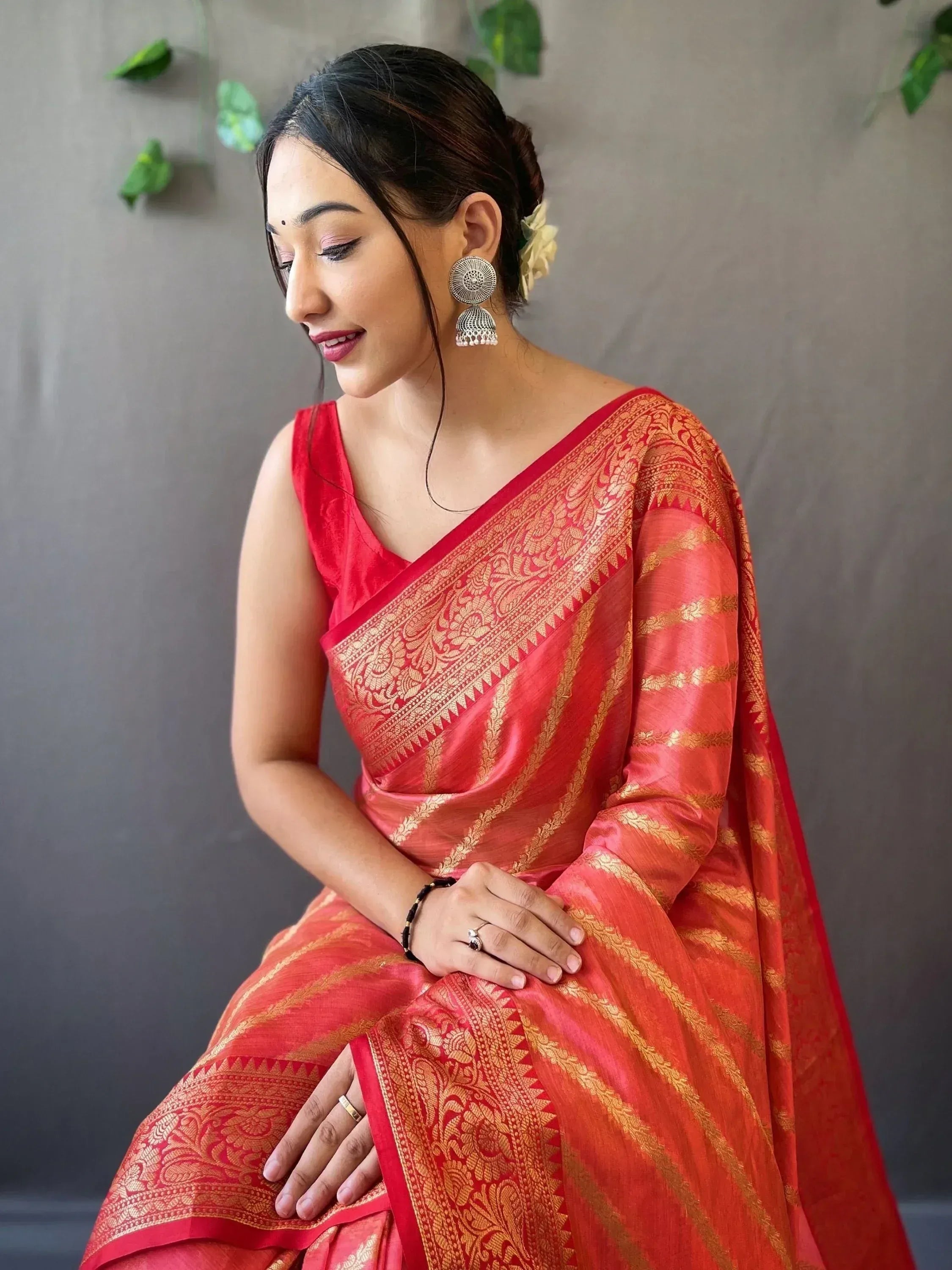 Woman in red and gold designer saree with intricate embroidery, traditional Indian ethnic wear