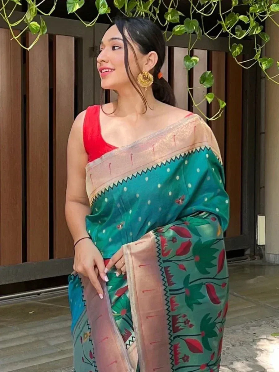 Woman in teal floral saree with red blouse, ethnic Indian wear, green leaf backdrop