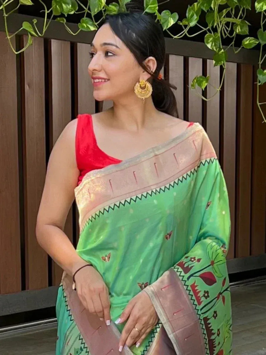 Woman in green printed saree with red blouse, gold earrings, outdoor garden setting
