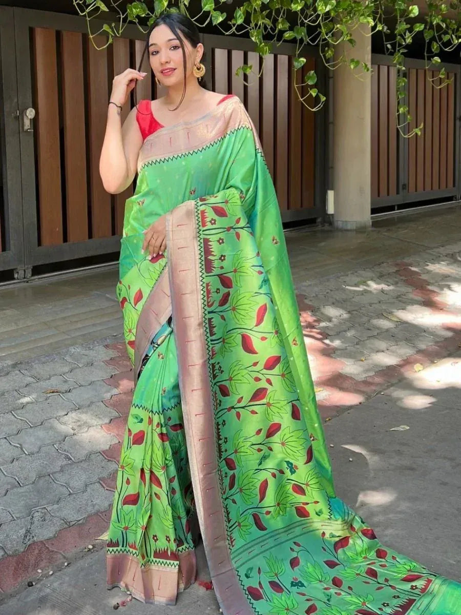 Woman in vibrant green printed saree with red floral motifs and gold border, styled with red blouse for ethnic wear.