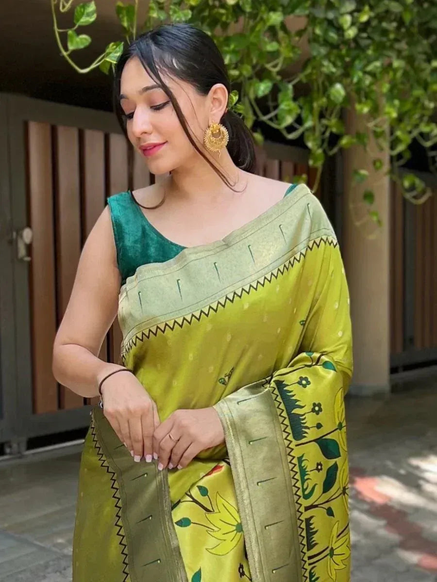 Woman in vibrant green printed saree with floral border and velvet blouse, styled with gold earrings