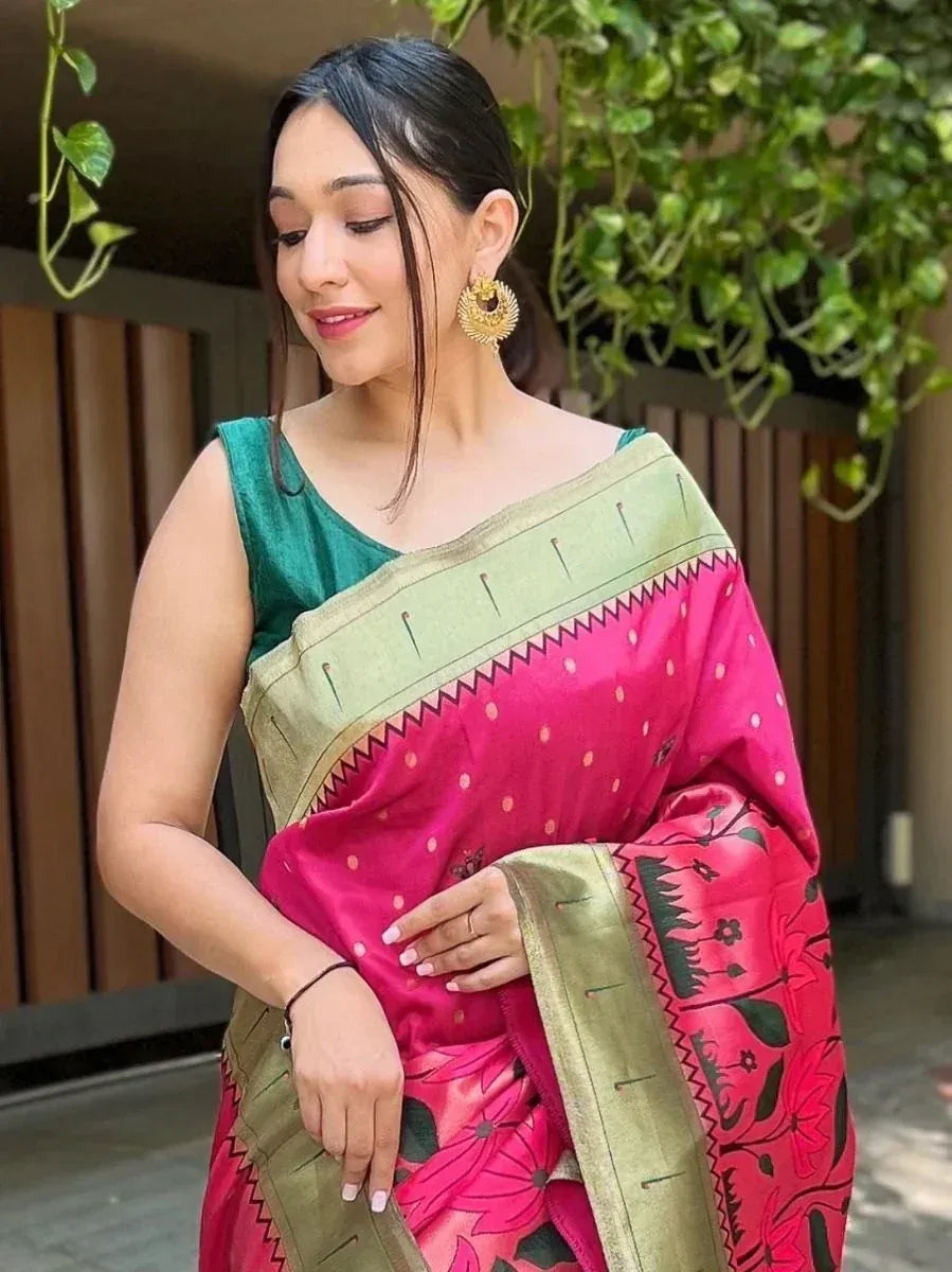 Woman in vibrant pink floral saree with green blouse and gold border, styled with traditional earrings