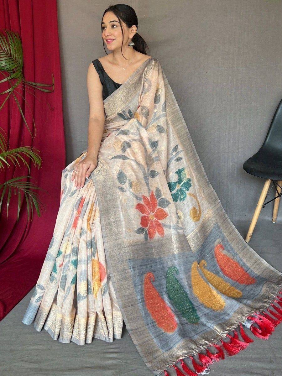 Woman in floral printed saree with colorful paisley border and red tassels, styled with black blouse for ethnic wear.