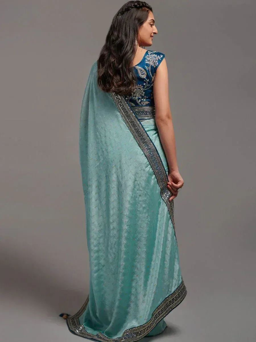 Woman in turquoise saree with embroidered blue blouse, showcasing elegant ethnic wear