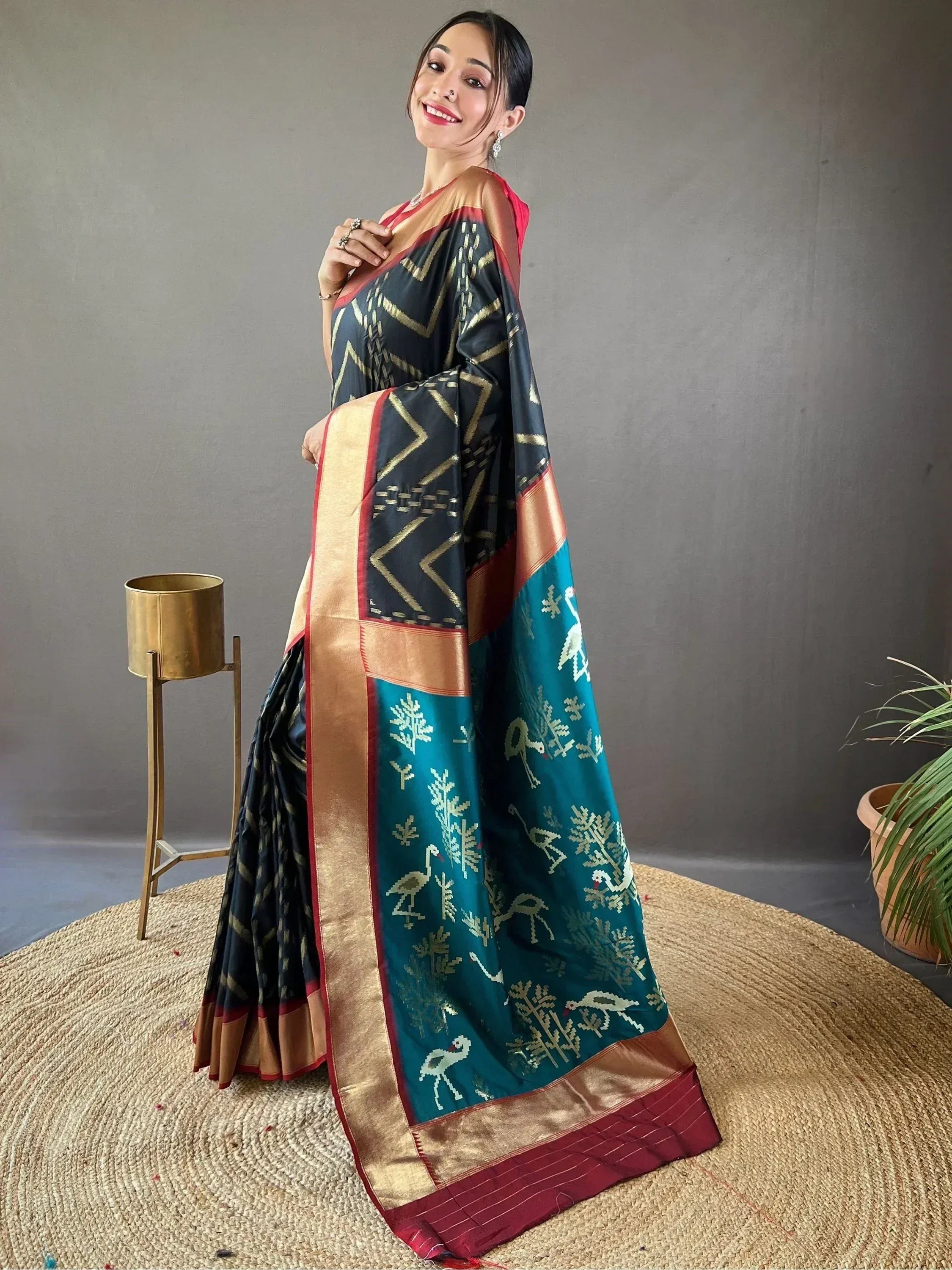 Woman in black and teal designer saree with gold geometric and bird motifs, perfect for ethnic occasions