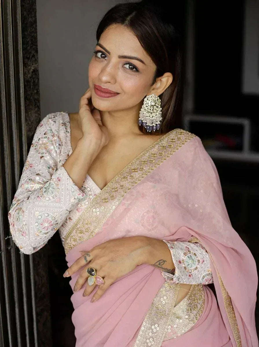 Pink embroidered saree with gold border and floral blouse, styled with statement earrings for Indian ethnic wear