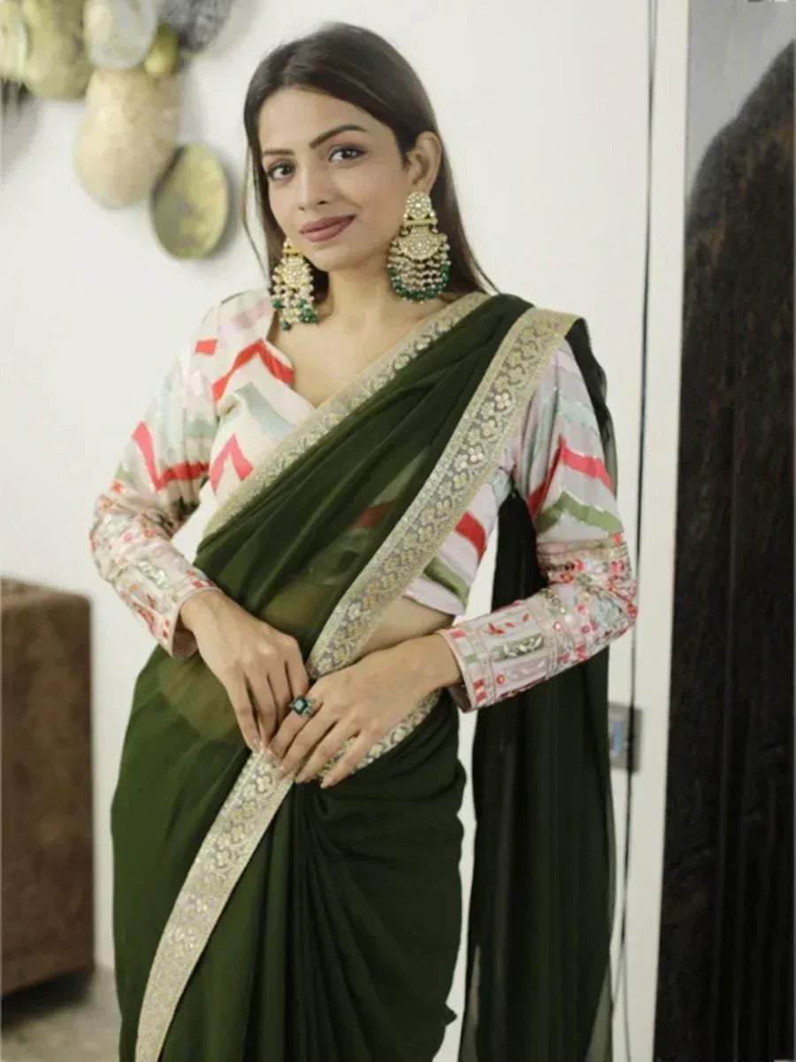 Woman in olive green saree with gold border and printed blouse, styled with jhumka earrings for ethnic wear