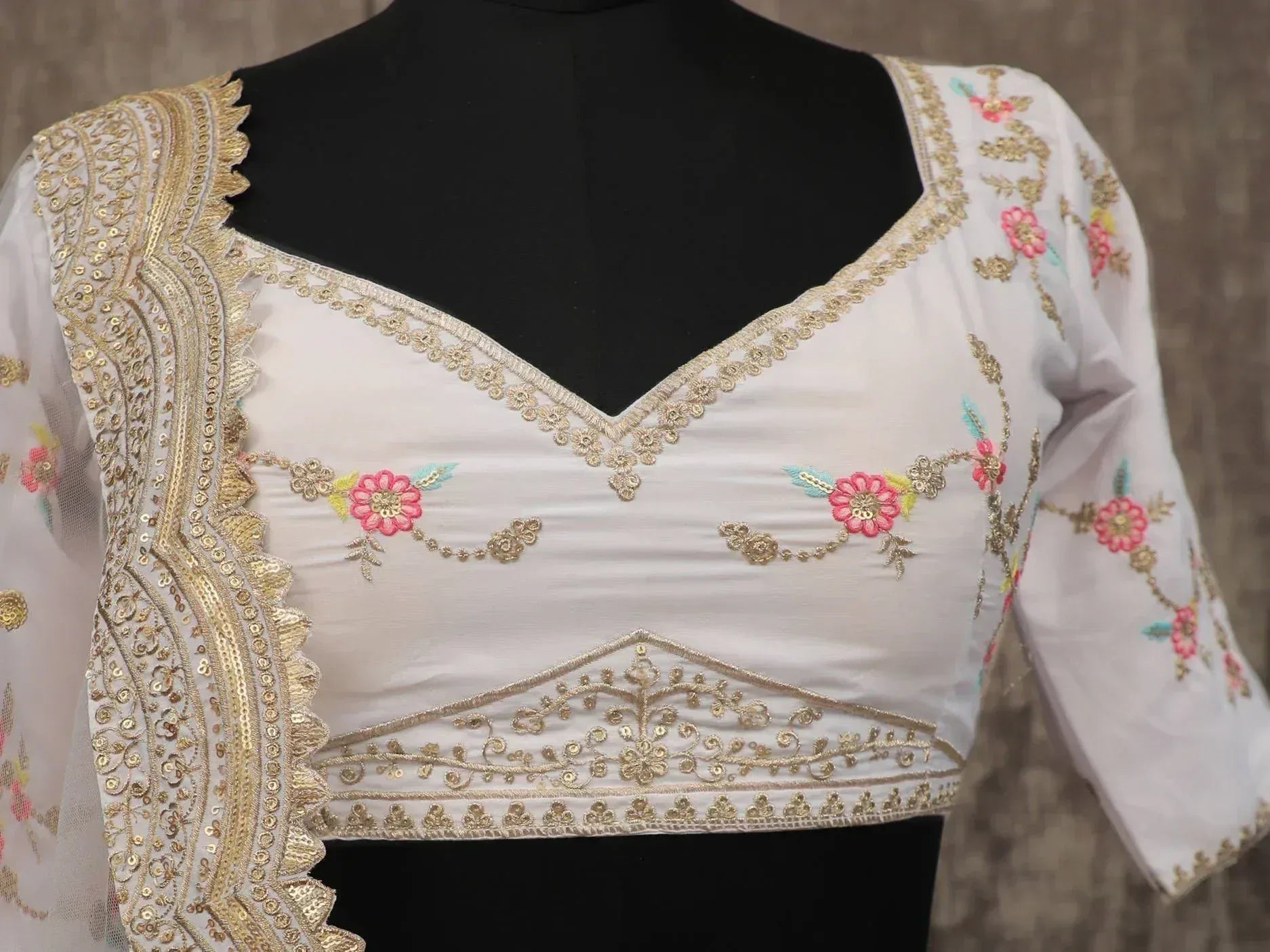 White embroidered lehenga choli blouse with gold detailing and floral motifs, ideal for Indian ethnic wear.