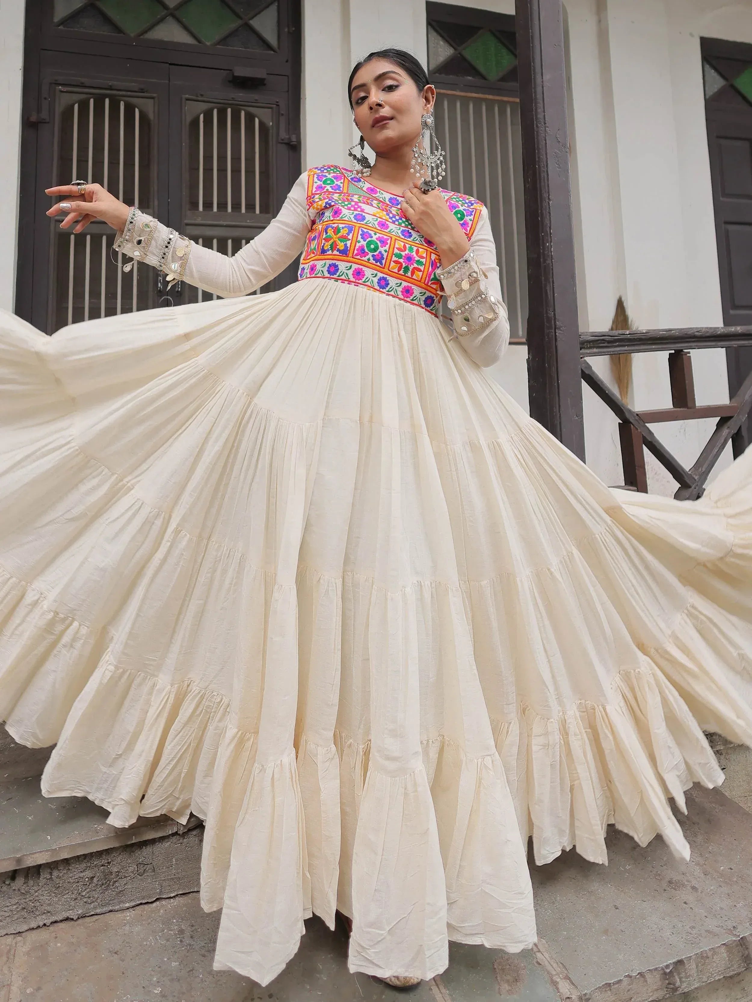 White ethnic gown with colorful floral embroidery and mirror work, perfect for Indian celebrations