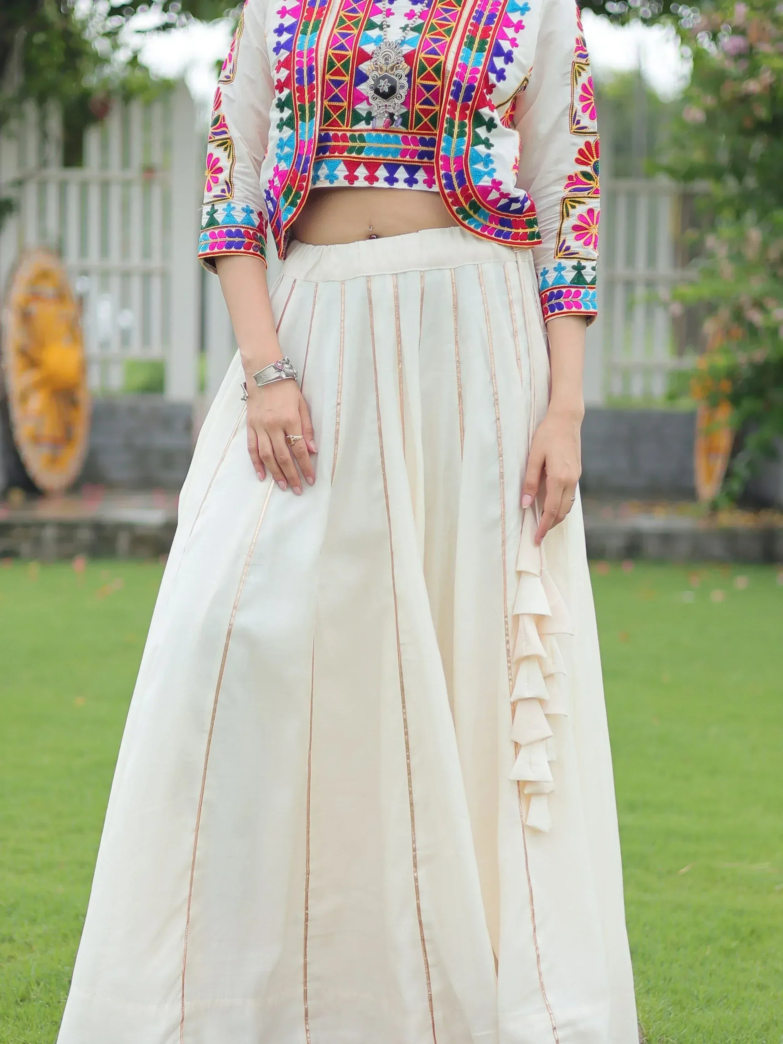 White ethnic lehenga with colorful embroidered crop top and ruffle details, perfect for Indian occasions.