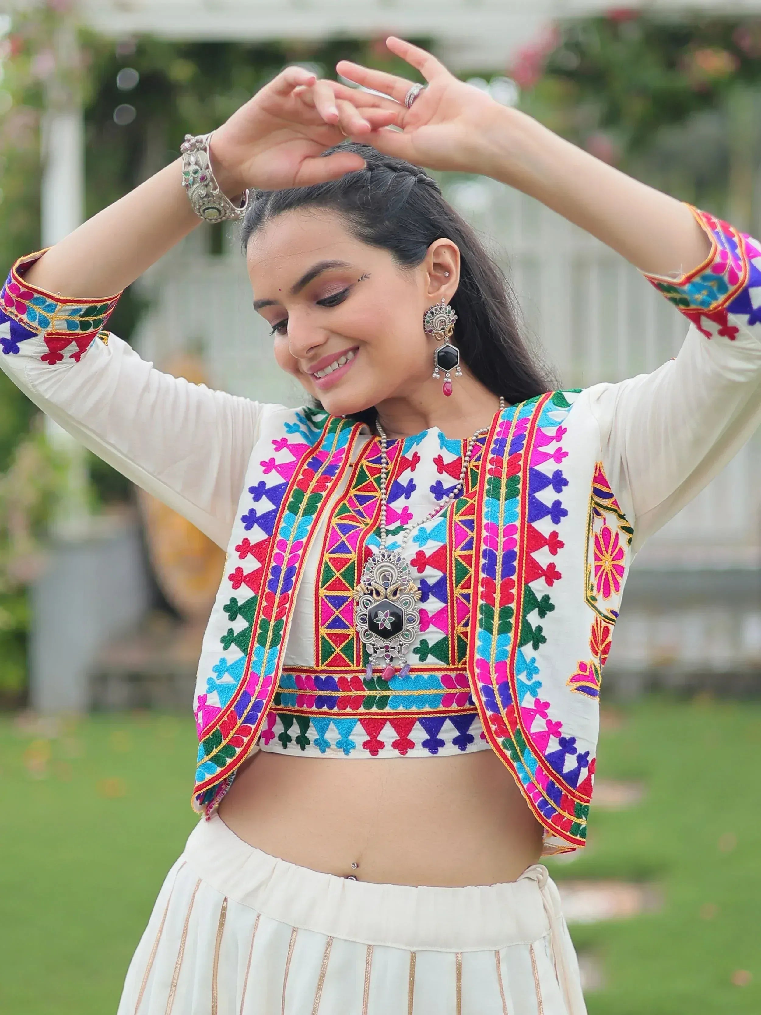 Woman in colorful embroidered Indian ethnic crop top and skirt, styled with traditional jewelry for festive occasions.