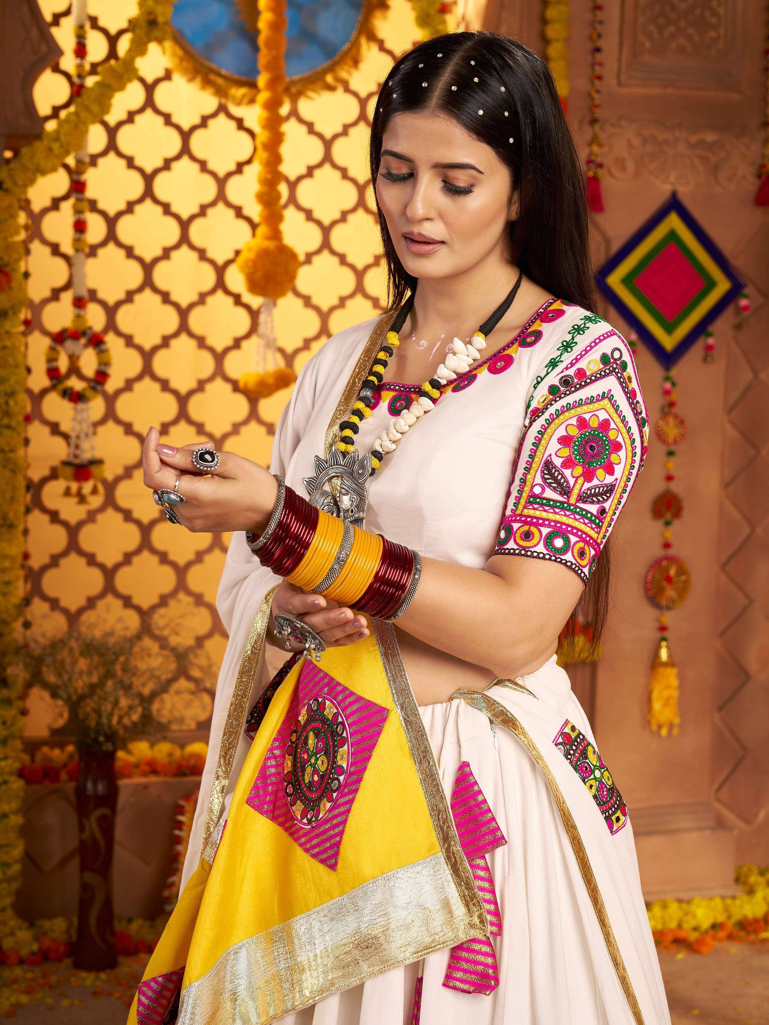 Woman in white embroidered choli with yellow dupatta, traditional Indian ethnic wear, festive jewelry and bangles