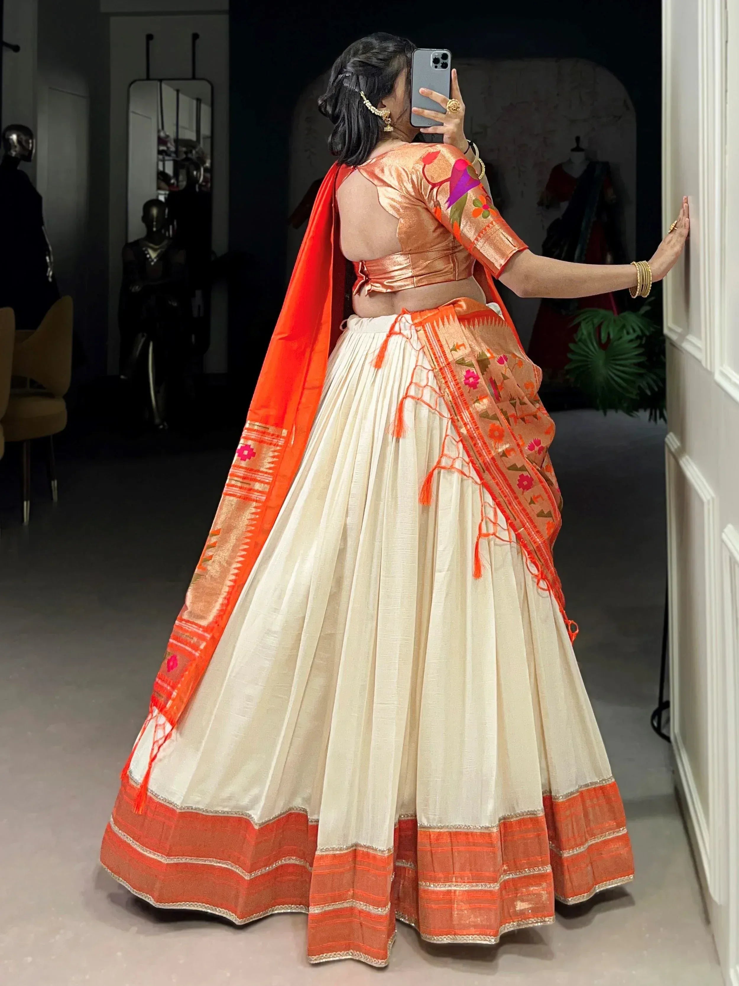 Woman in cream and orange designer lehenga choli with embroidered dupatta, ethnic Indian wear
