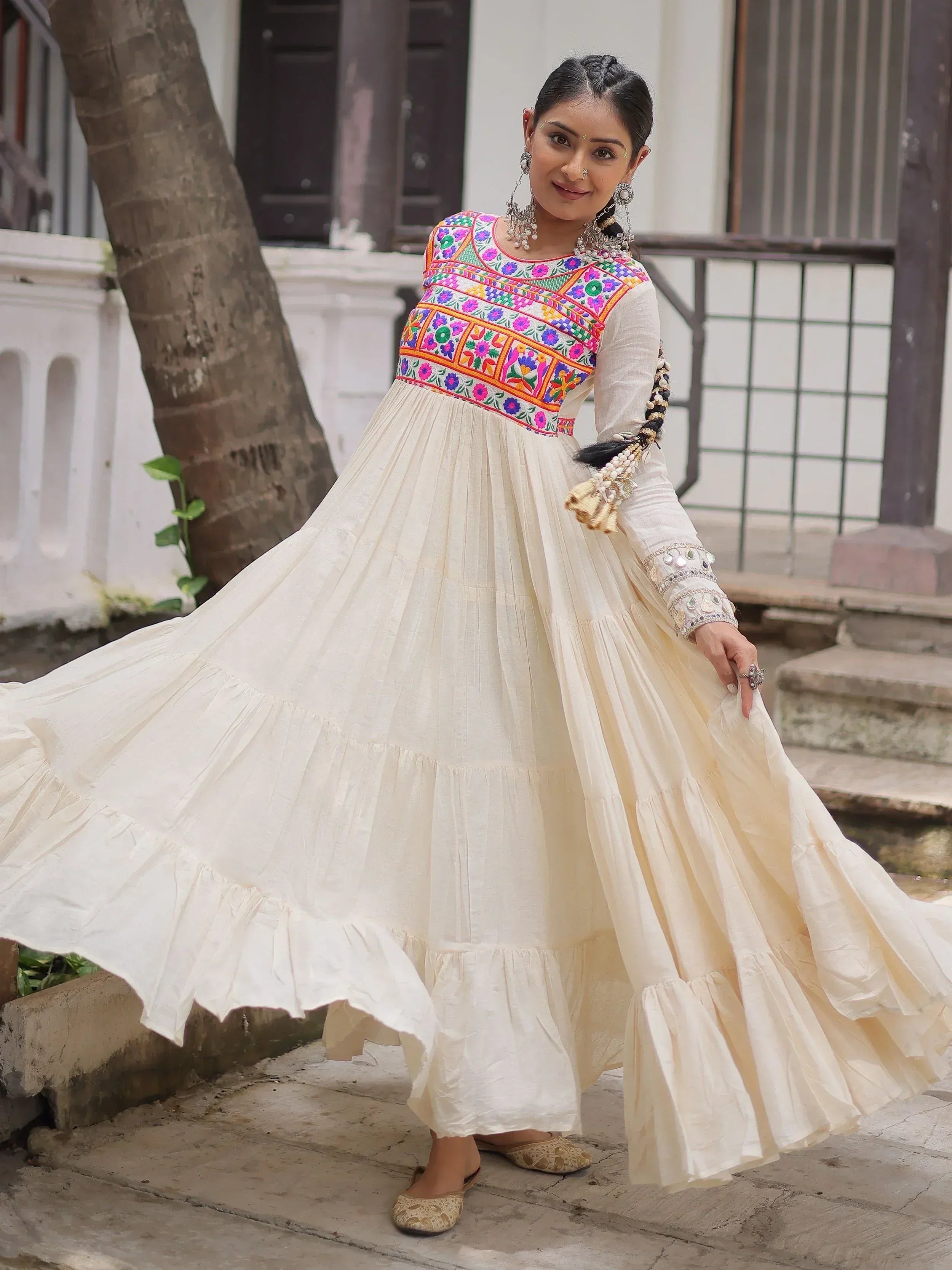 Woman in white ethnic gown with colorful floral embroidery, perfect for Indian festive occasions