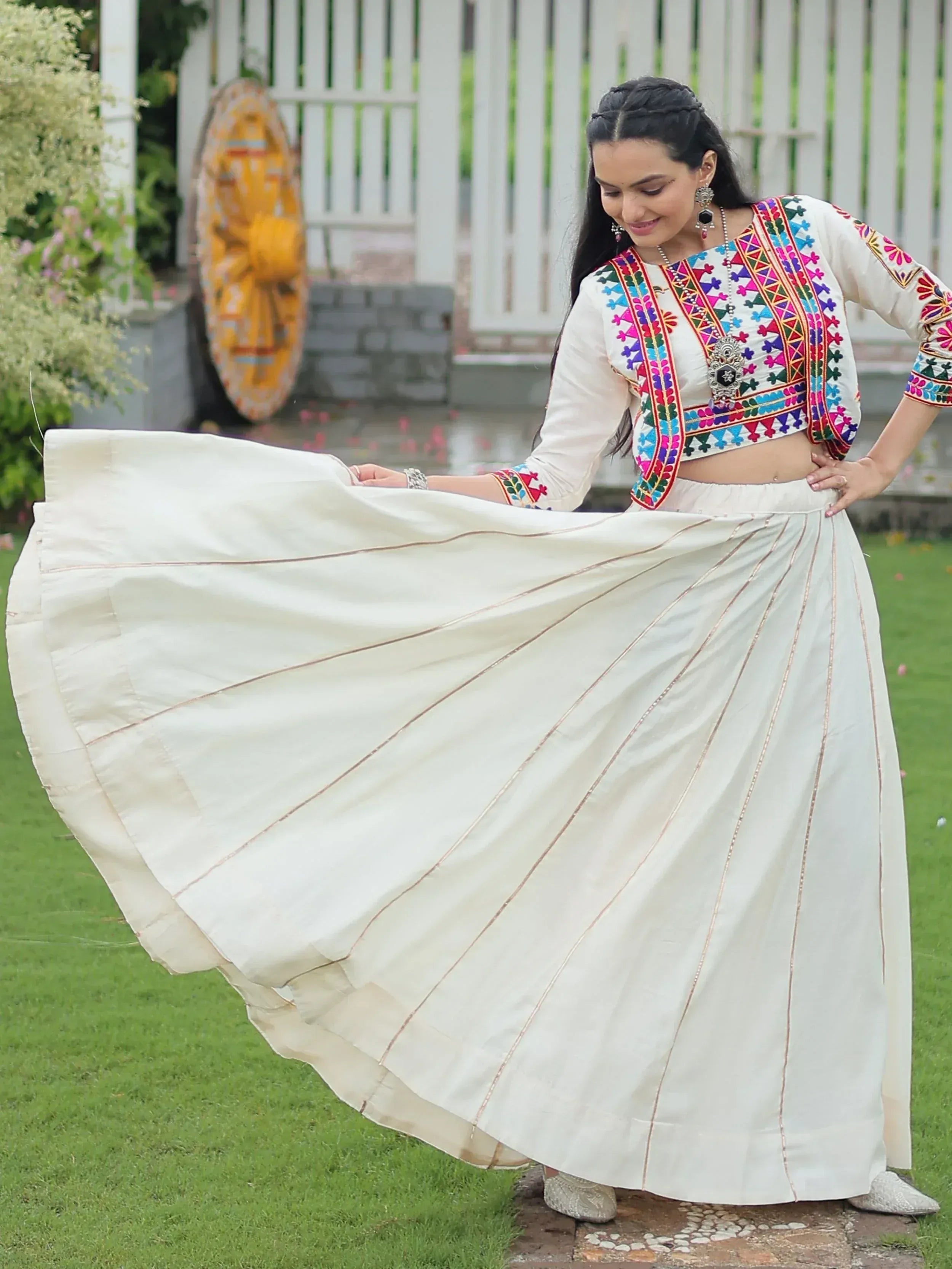Woman in white embroidered ethnic crop top and flared skirt, showcasing Indian designer wear outdoors