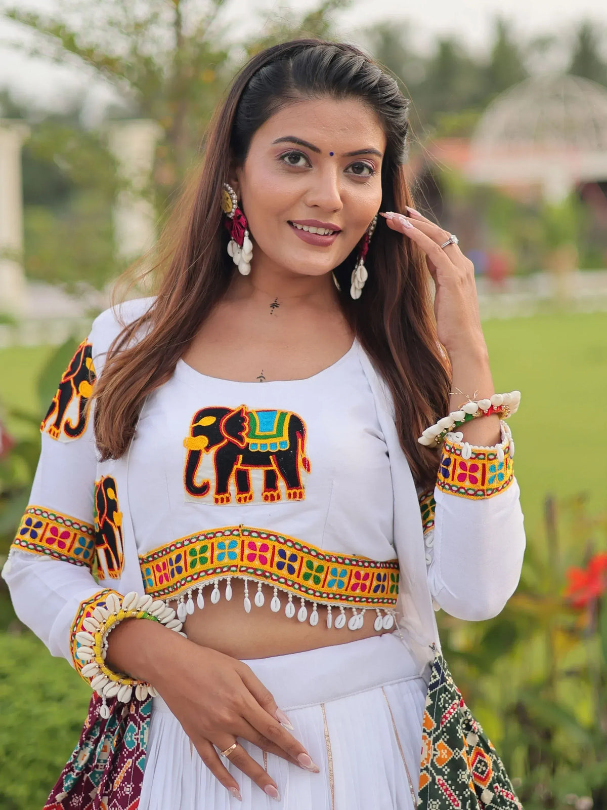 White ethnic crop top with colorful elephant embroidery and shell detailing, paired with matching skirt for festive wear