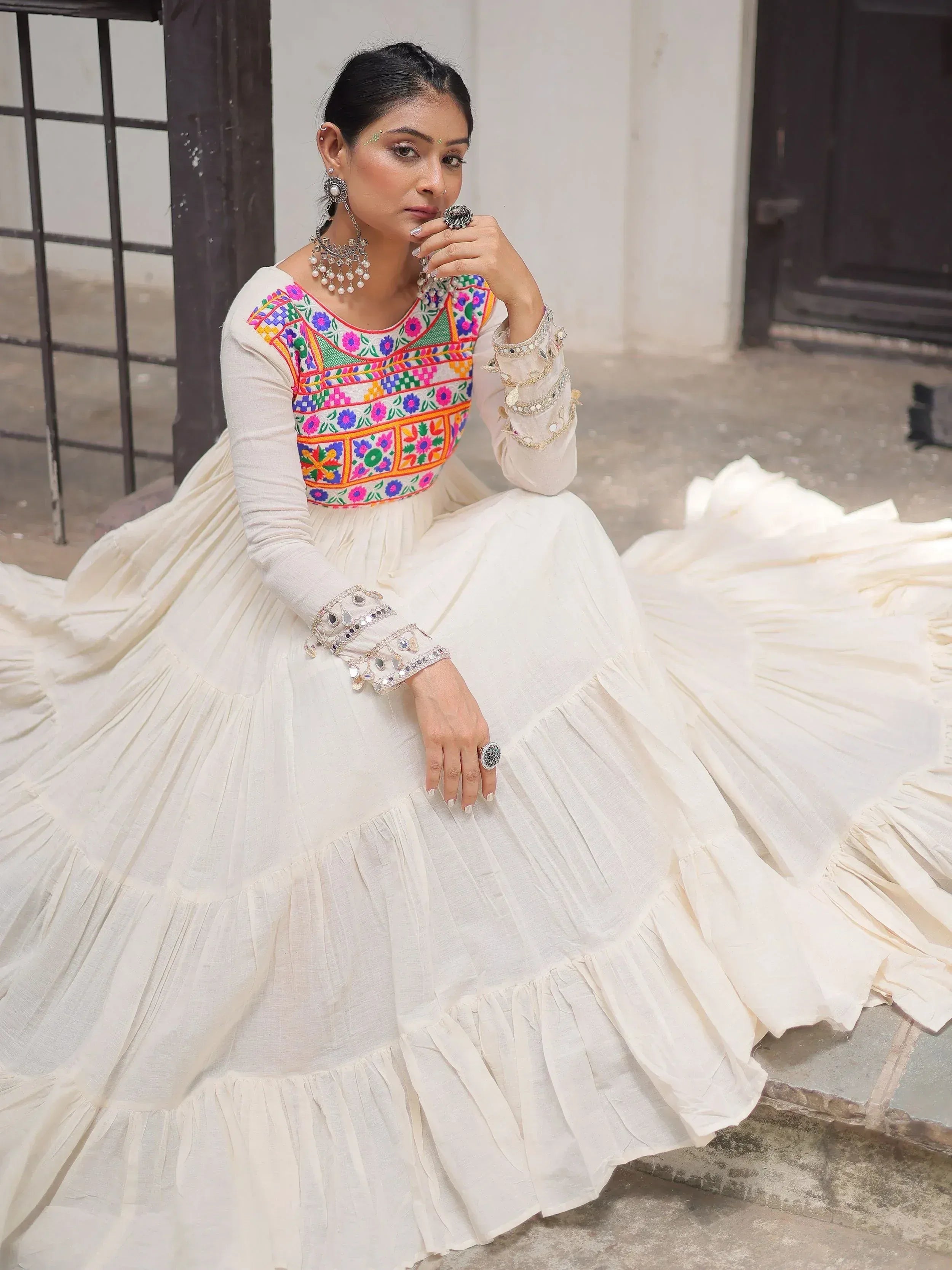 White ethnic gown with colorful floral embroidery and mirror work, perfect for Indian occasions