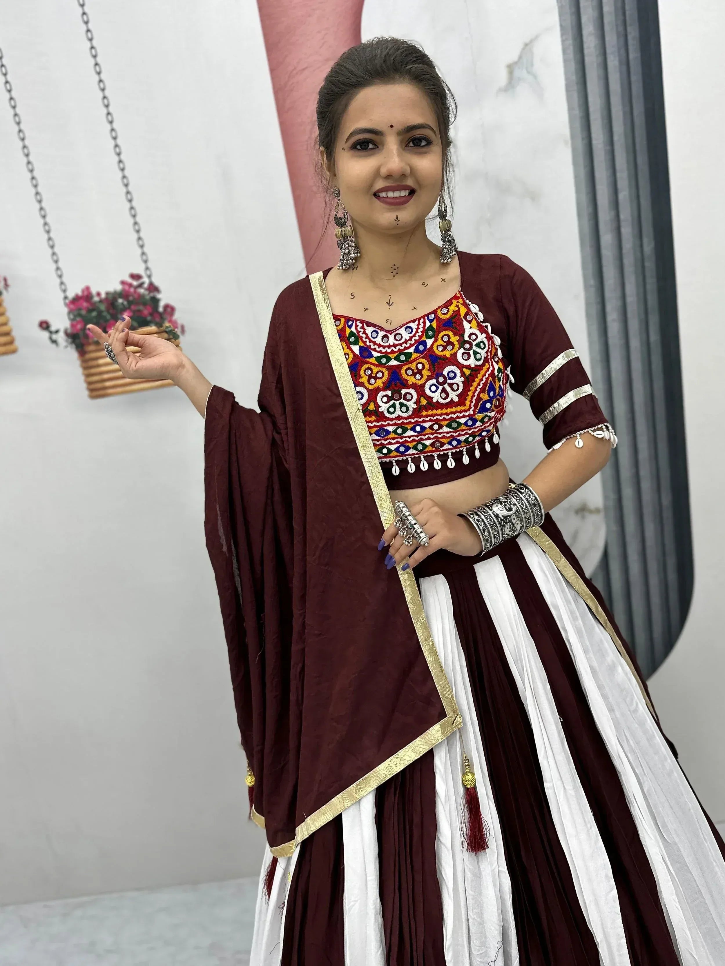 Maroon and white ethnic lehenga choli with colorful mirror work and gold trim, perfect for Indian celebrations.