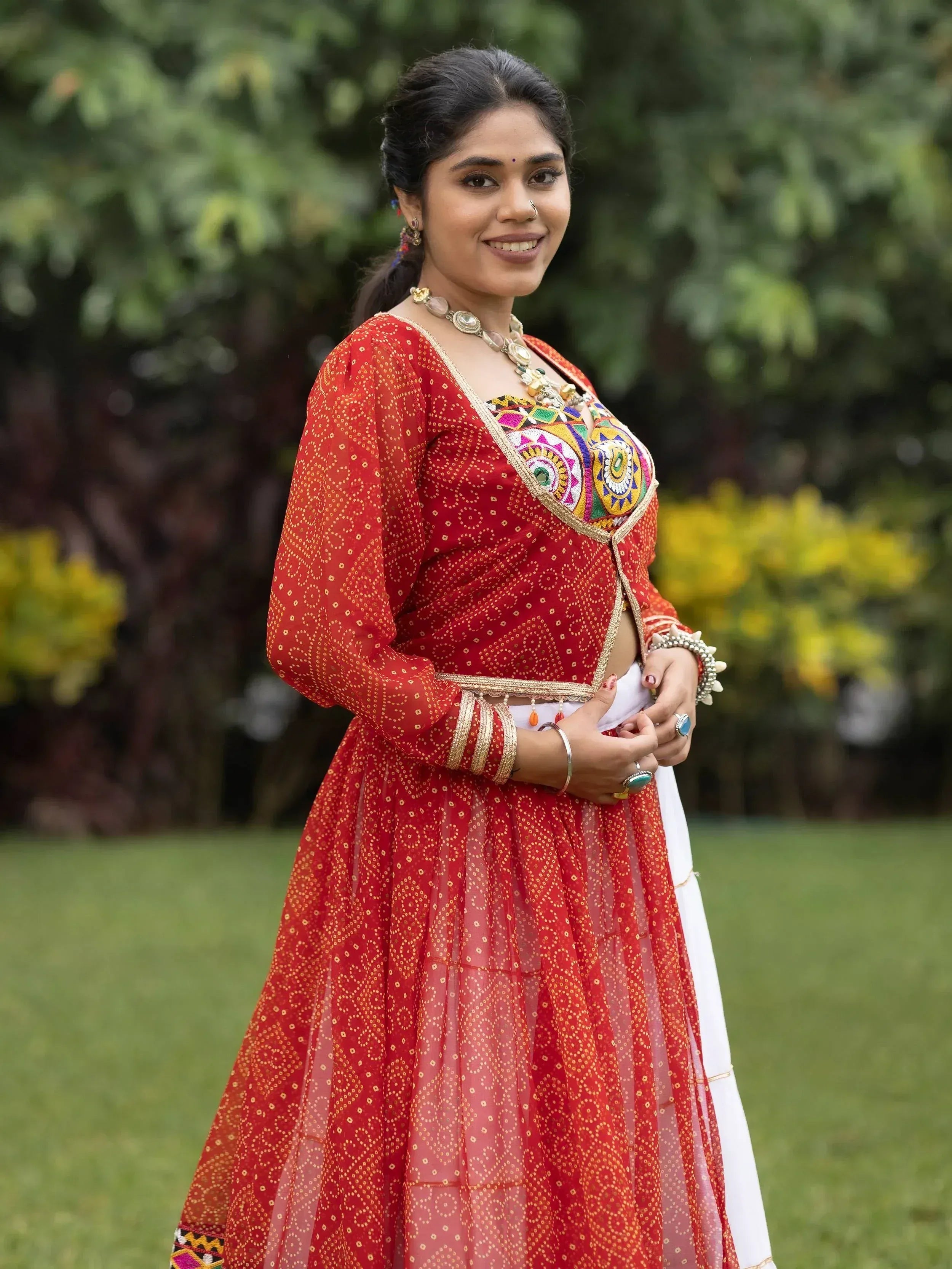 Woman in red embroidered lehenga choli with colorful mirror work, perfect for Indian ethnic wear occasions