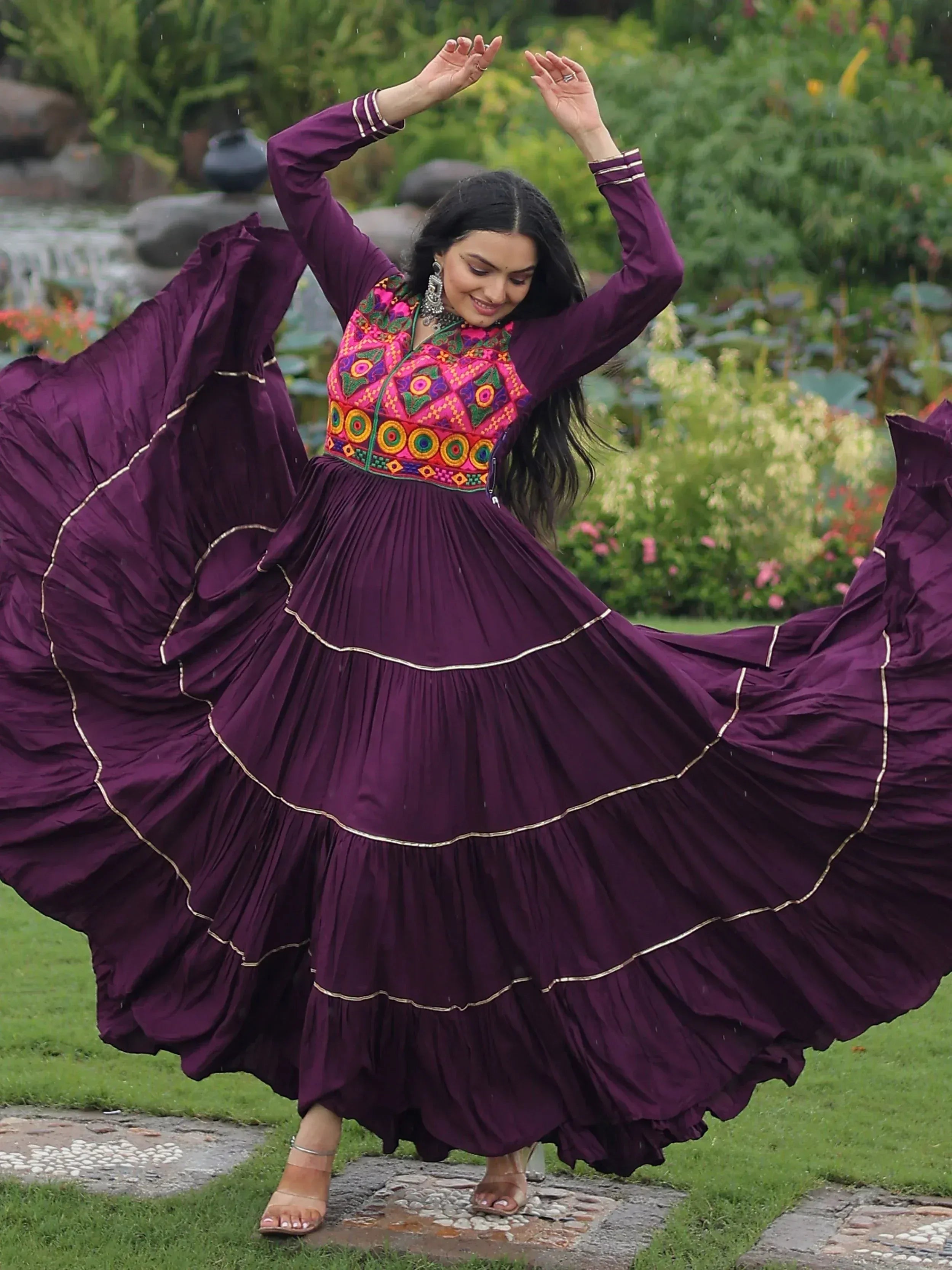 Woman twirling in purple ethnic gown with vibrant embroidery, perfect for festive occasions.
