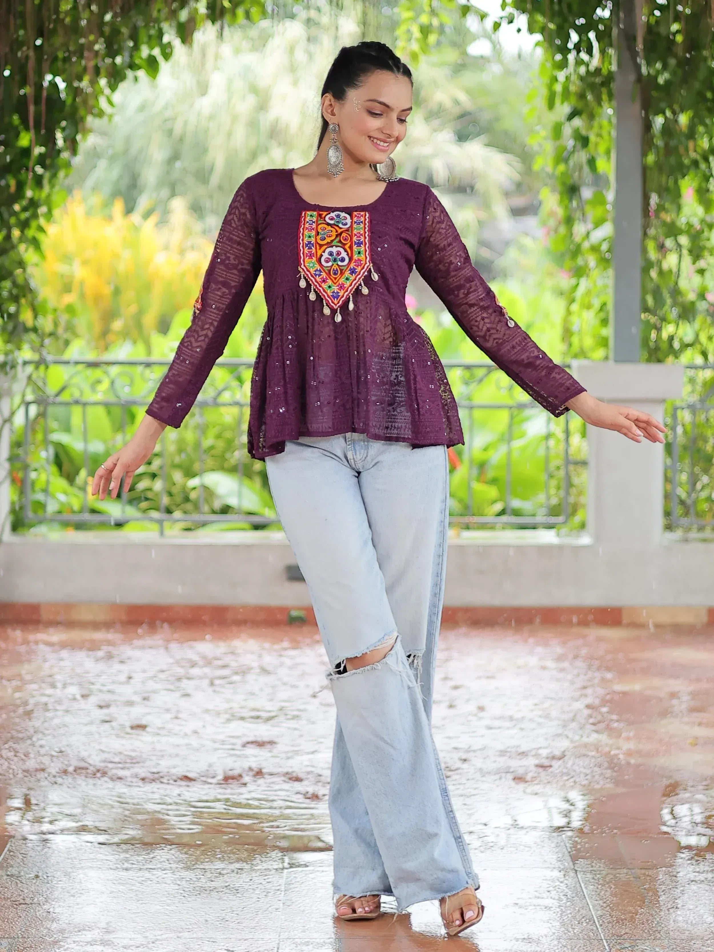 Woman in purple embroidered ethnic top with jeans, dancing in rain