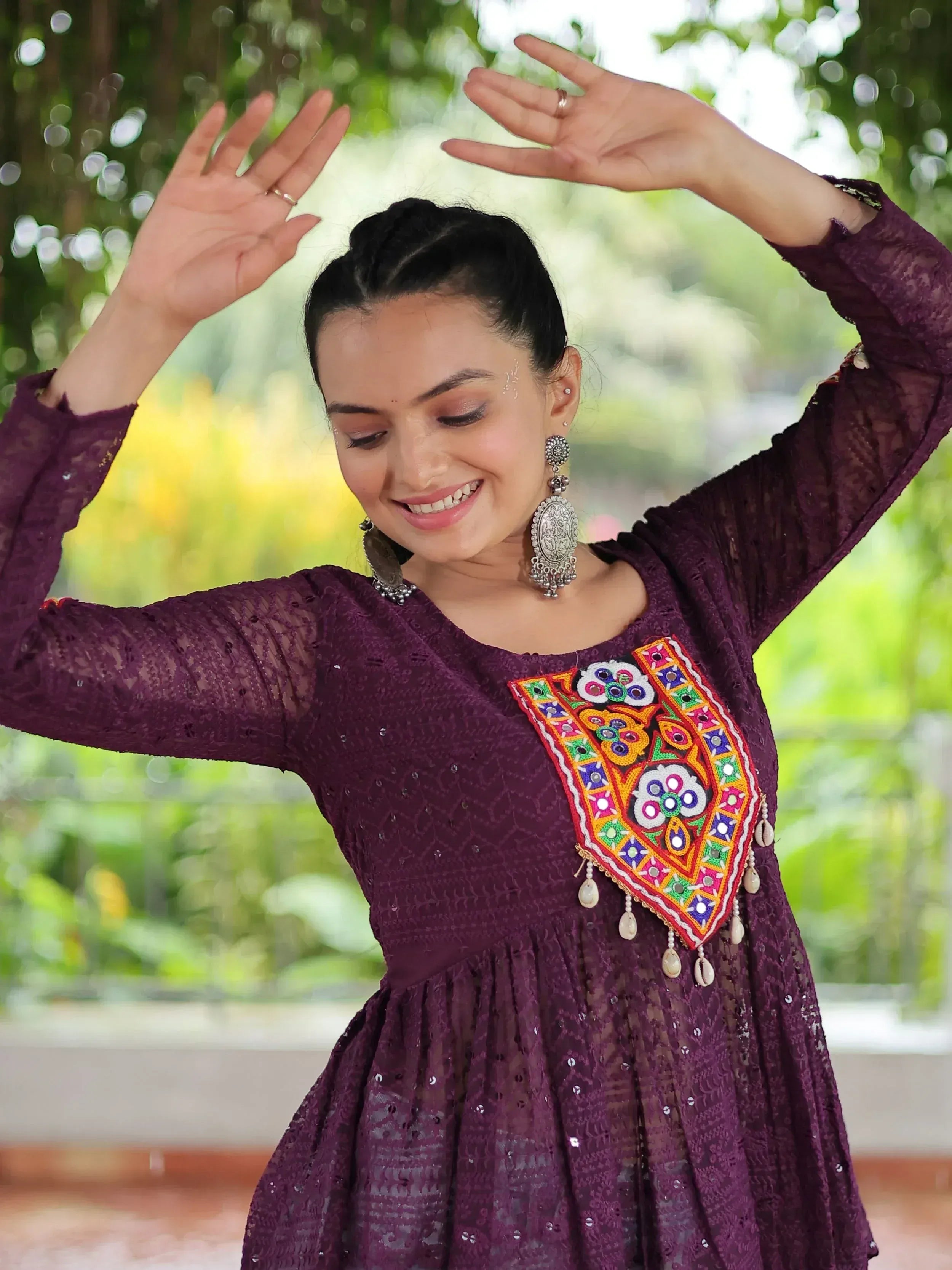 Woman in purple ethnic gown with colorful mirror work, dancing outdoors
