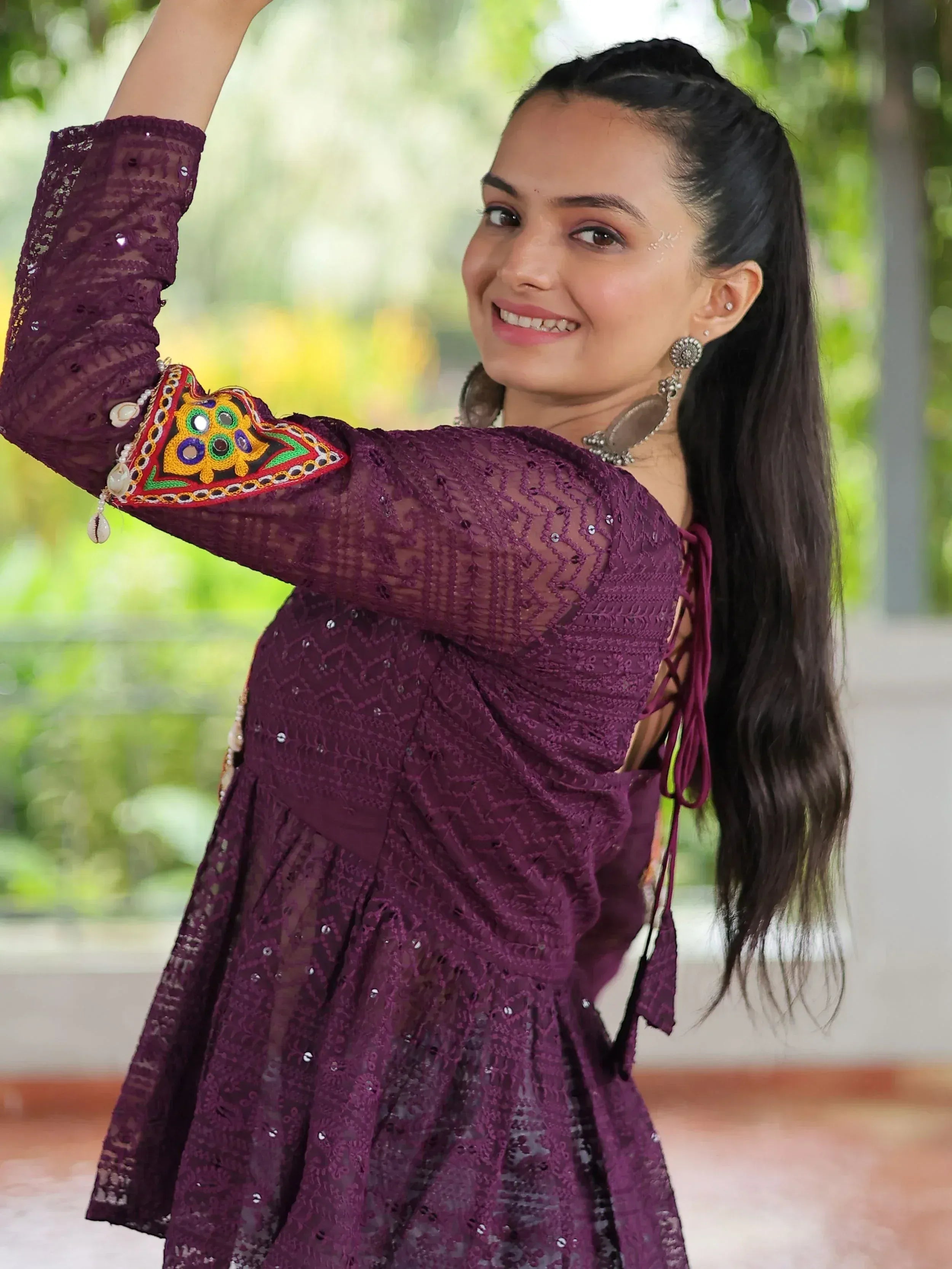 Woman in purple ethnic gown with mirror work, lace, and sequins, perfect for Indian festive occasions.