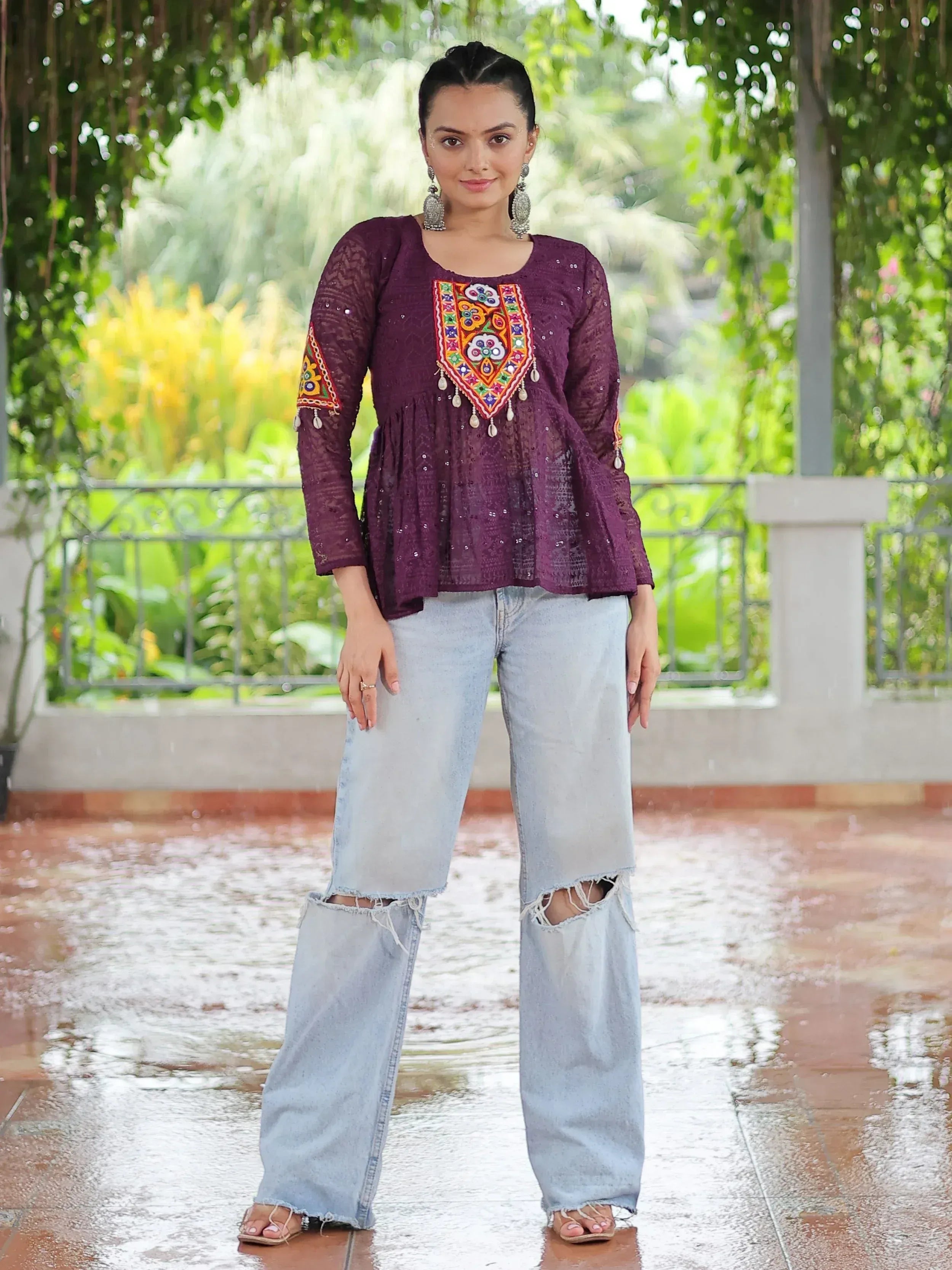 Purple embroidered ethnic top with mirror work, paired with ripped jeans, perfect for casual Indian wear.