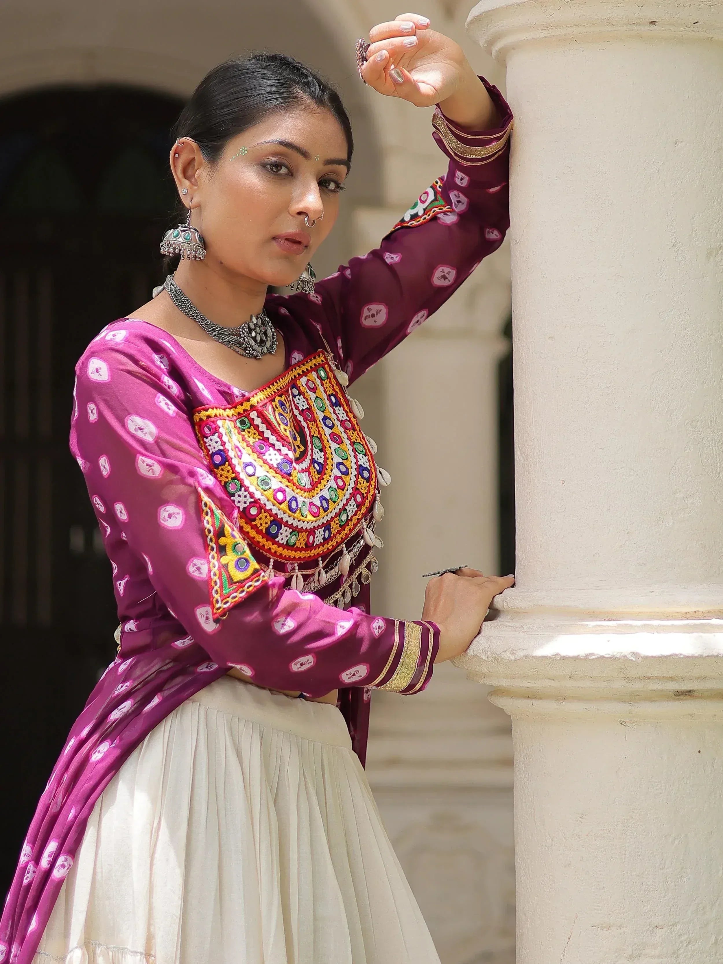 Woman in maroon and pink embroidered ethnic top with white skirt, traditional Indian wear