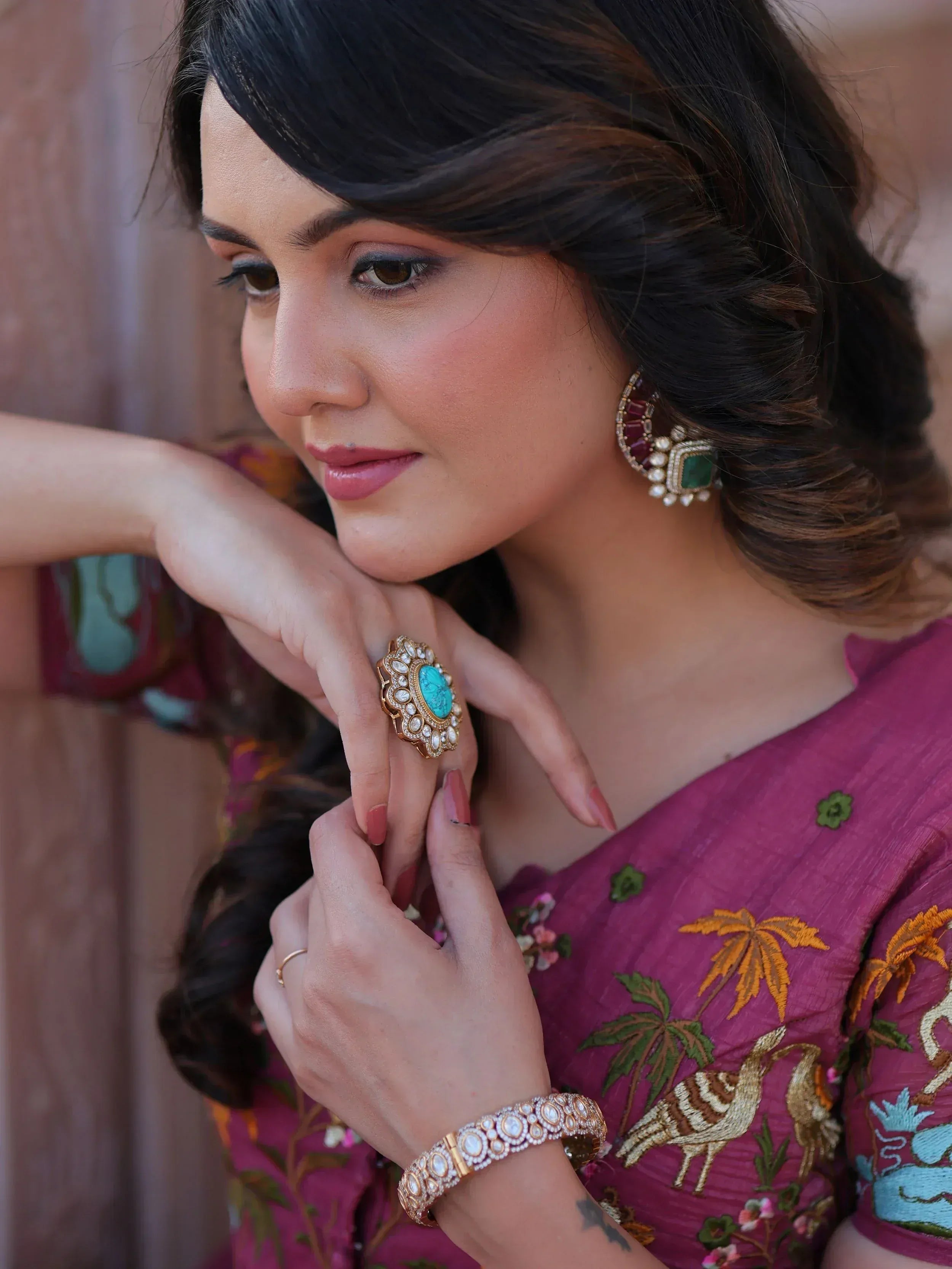 Woman in embroidered ethnic gown with turquoise jewelry, showcasing designer Indian wear