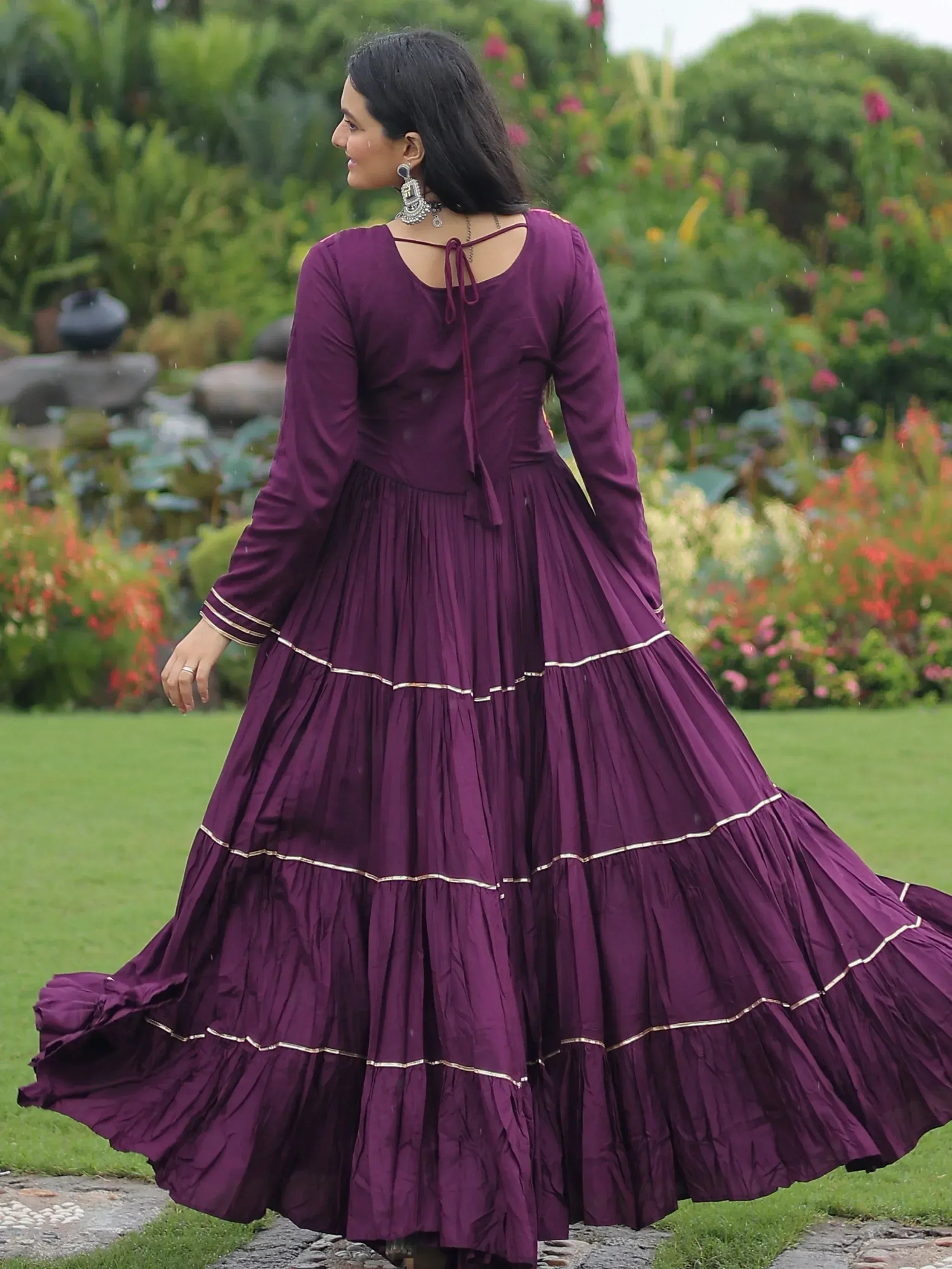 Purple tiered ethnic gown with gold trim, back view in garden setting