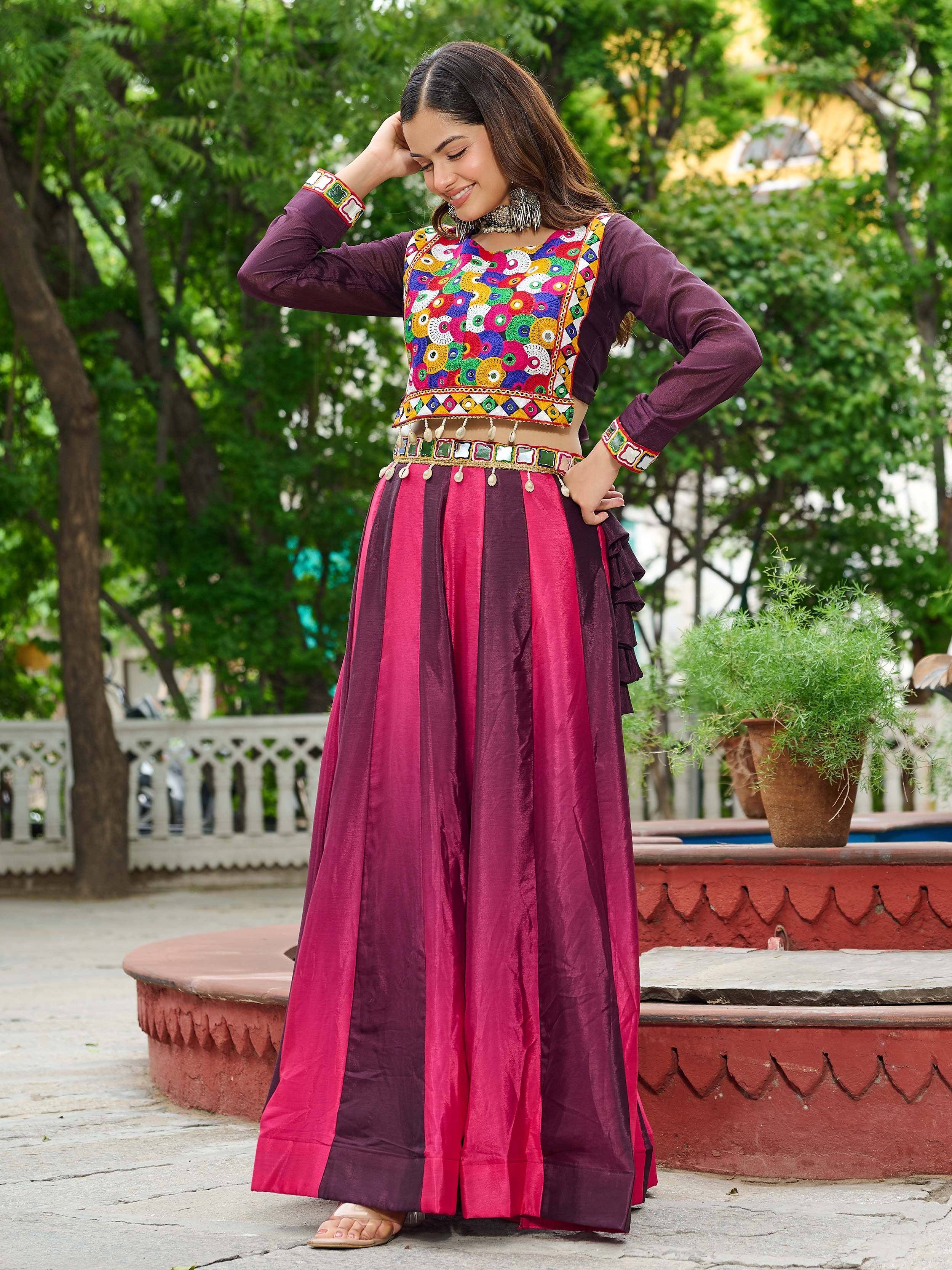 Woman in colorful embroidered Indian ethnic wear with mirror work, pink and maroon striped skirt, perfect for festive occasions.