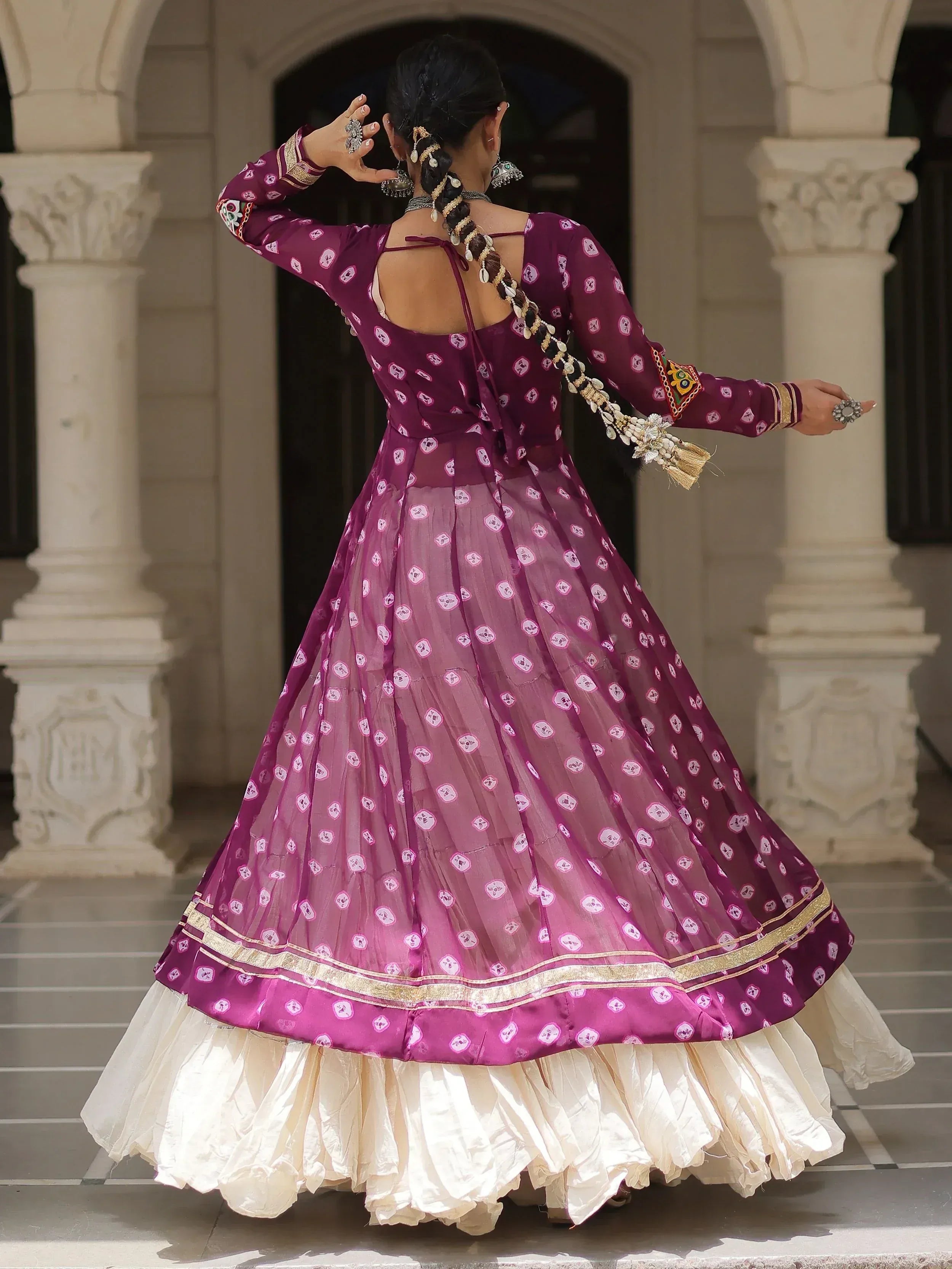 Woman in purple printed ethnic gown with gold trim, back view, traditional Indian wear