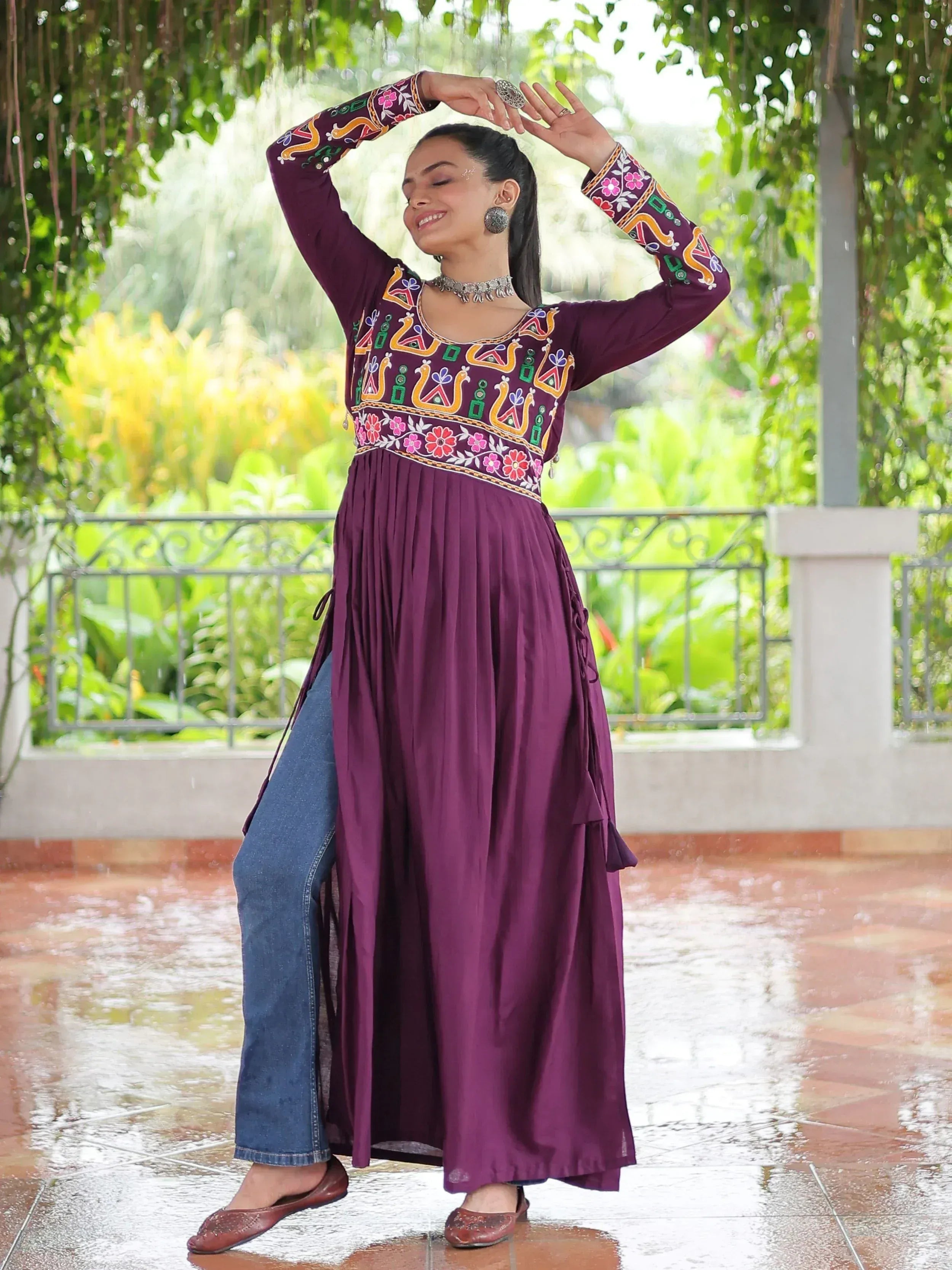 Purple embroidered ethnic gown with floral patterns, paired with jeans, worn outdoors in rain