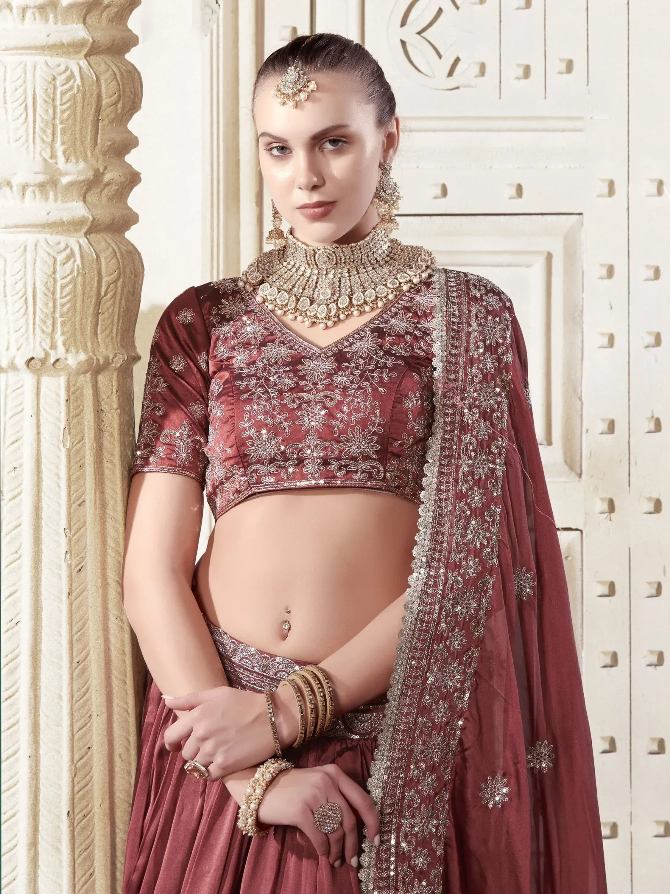 Maroon embroidered lehenga choli with gold jewelry, perfect for Indian weddings and festive occasions