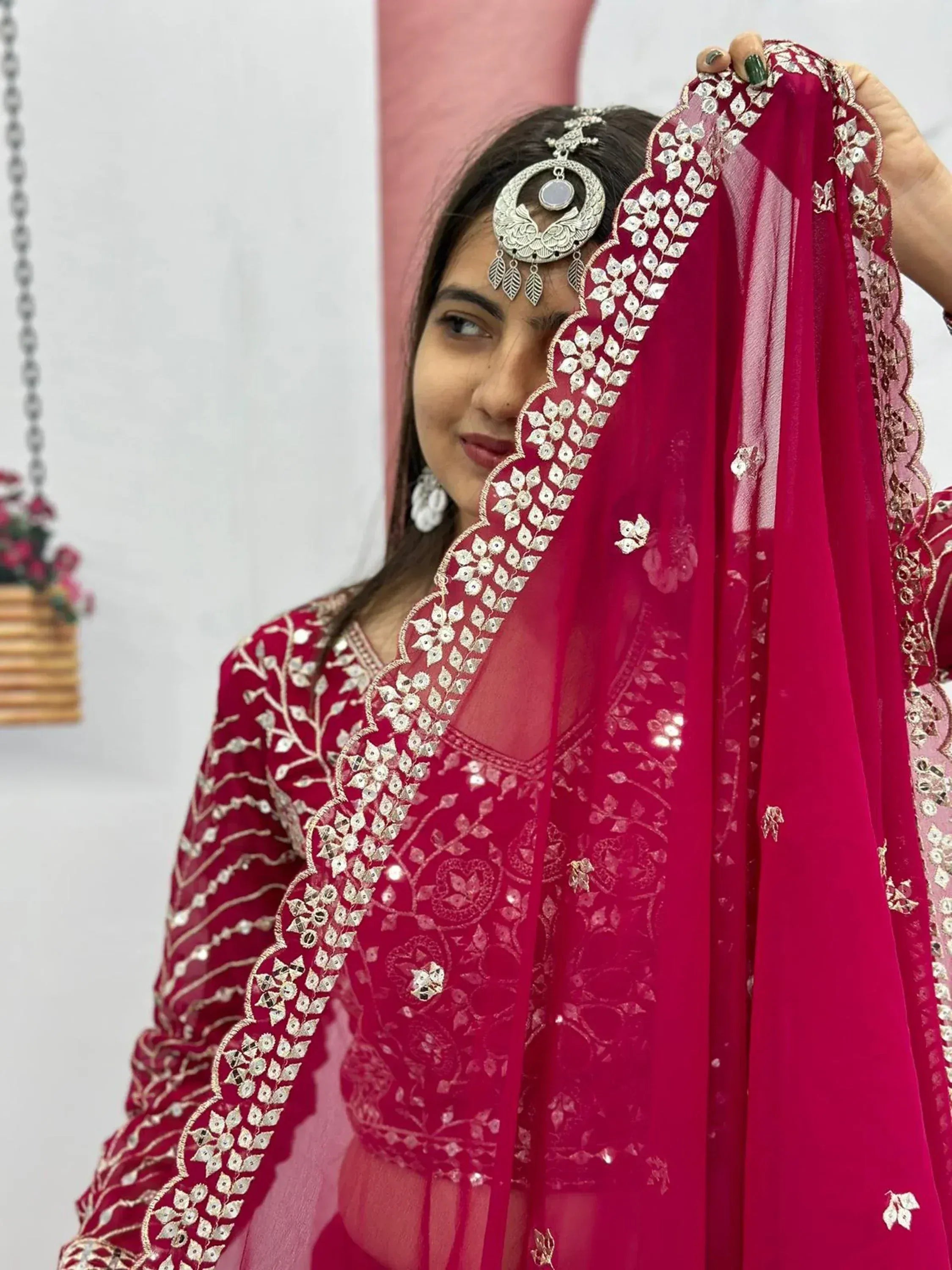 Woman in maroon Indian ethnic wear with mirror work dupatta and traditional jewelry