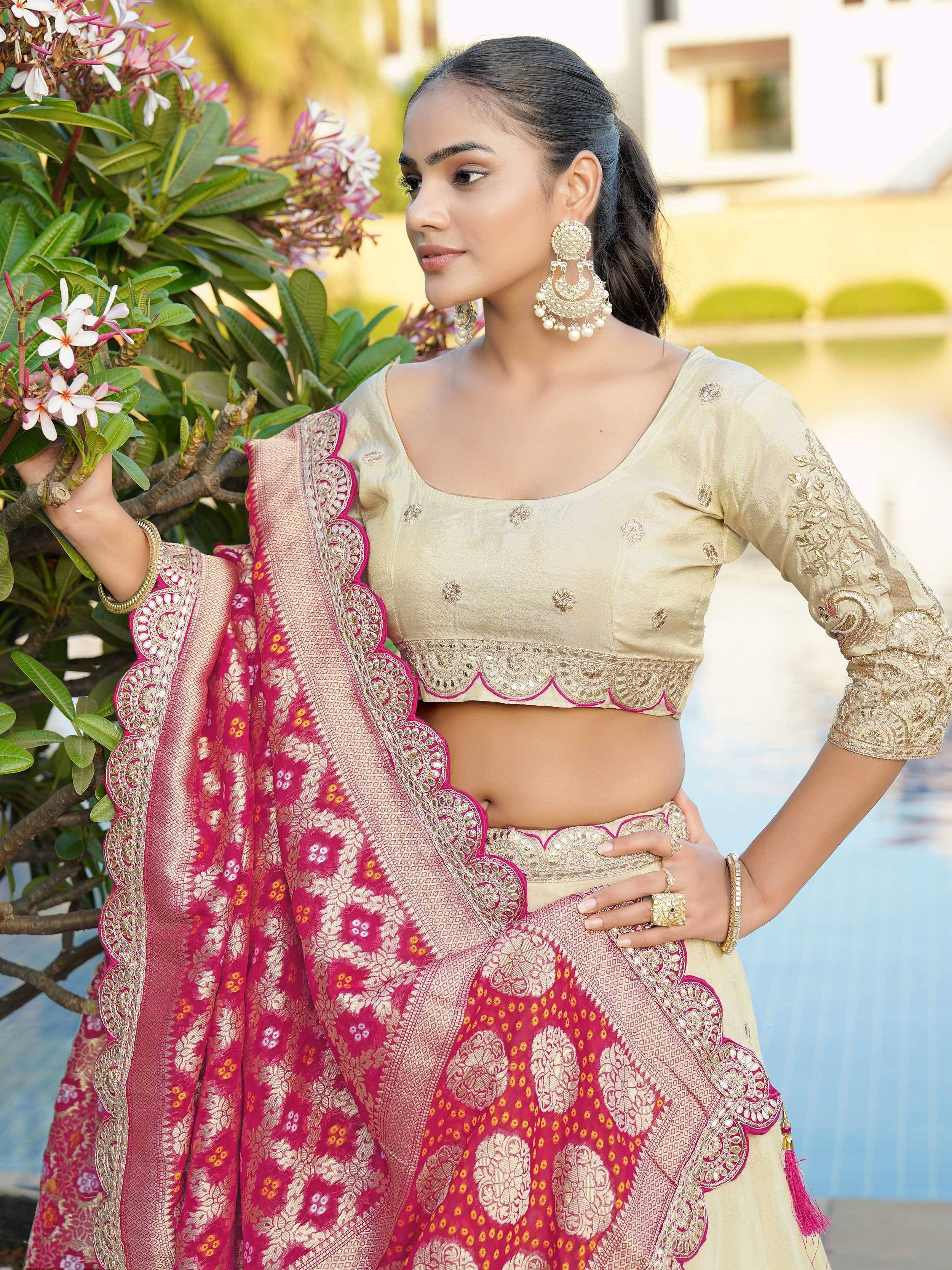 Elegant woman in designer lehenga choli with gold embroidery, pink dupatta, and floral backdrop