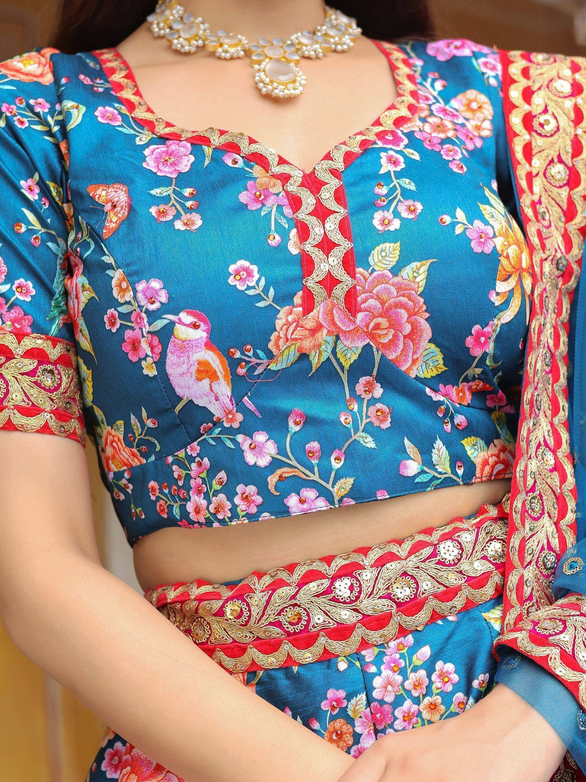 Blue floral lehenga choli with bird print, red gold embroidery, and matching jewelry for Indian ethnic wear