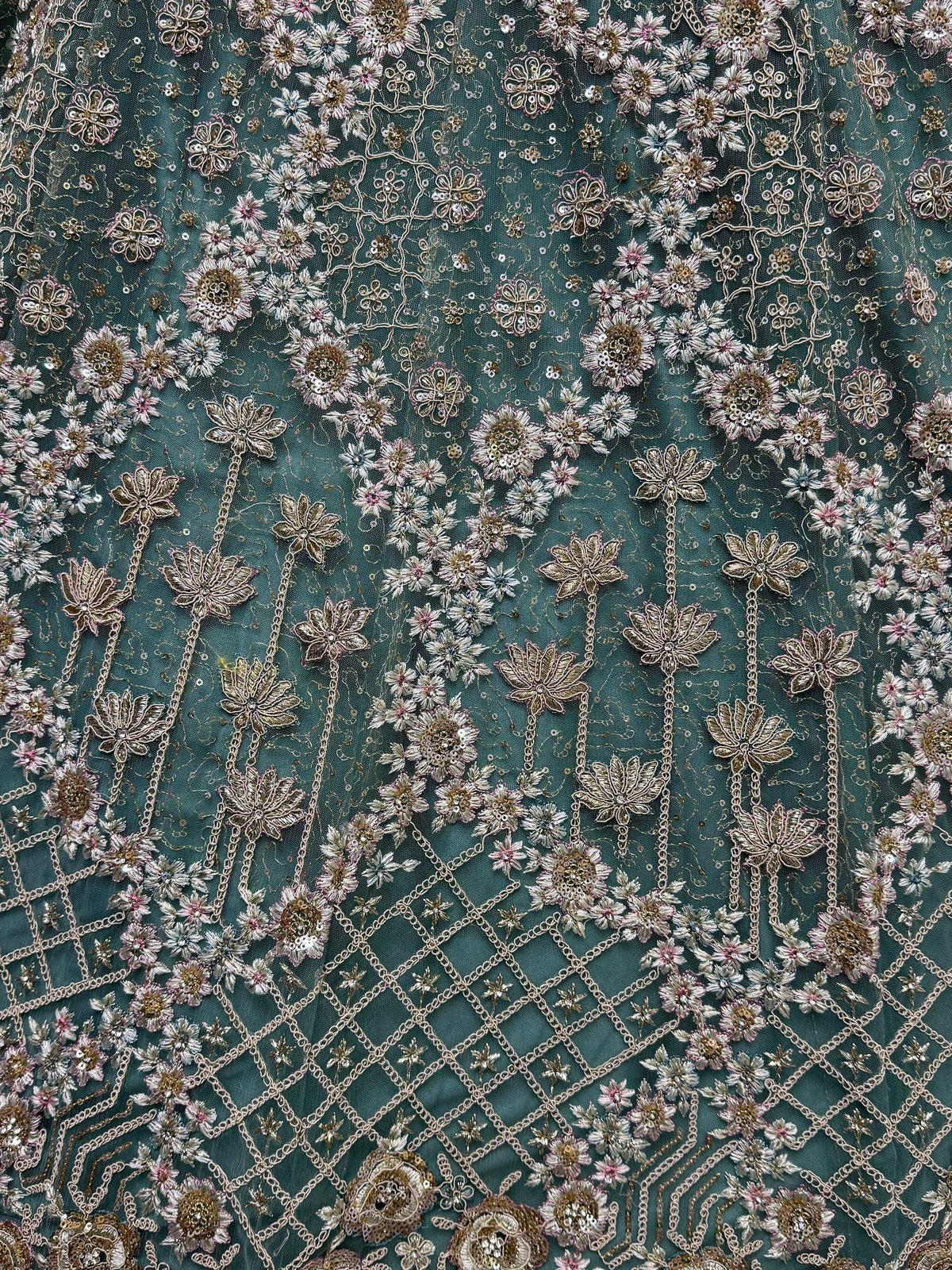 Teal ethnic fabric with floral embroidery, sequins, and gold chain detailing for designer lehenga or saree.