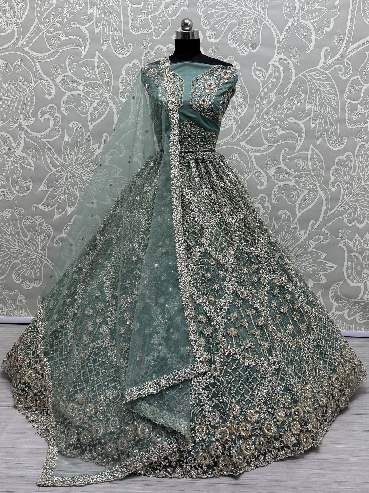 Elegant sage green designer lehenga choli with heavy silver embroidery and net dupatta, perfect for weddings.