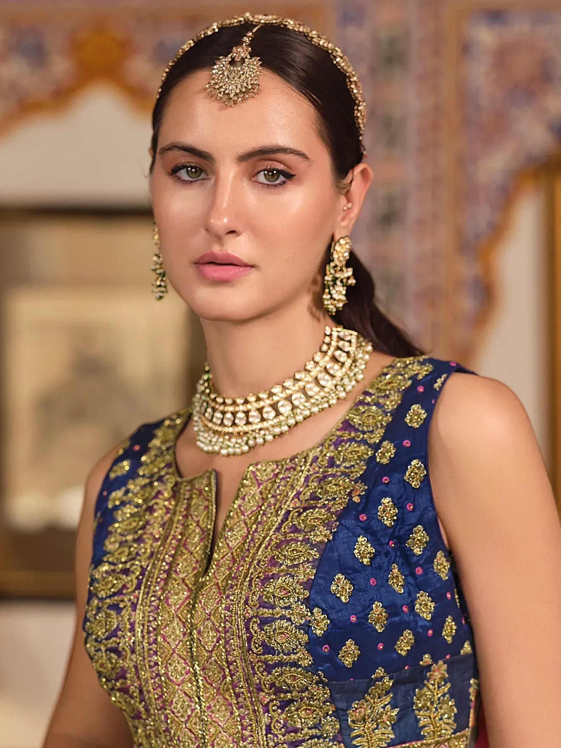 Woman in blue and gold embroidered ethnic gown with traditional jewelry, perfect for Indian weddings or festive occasions.